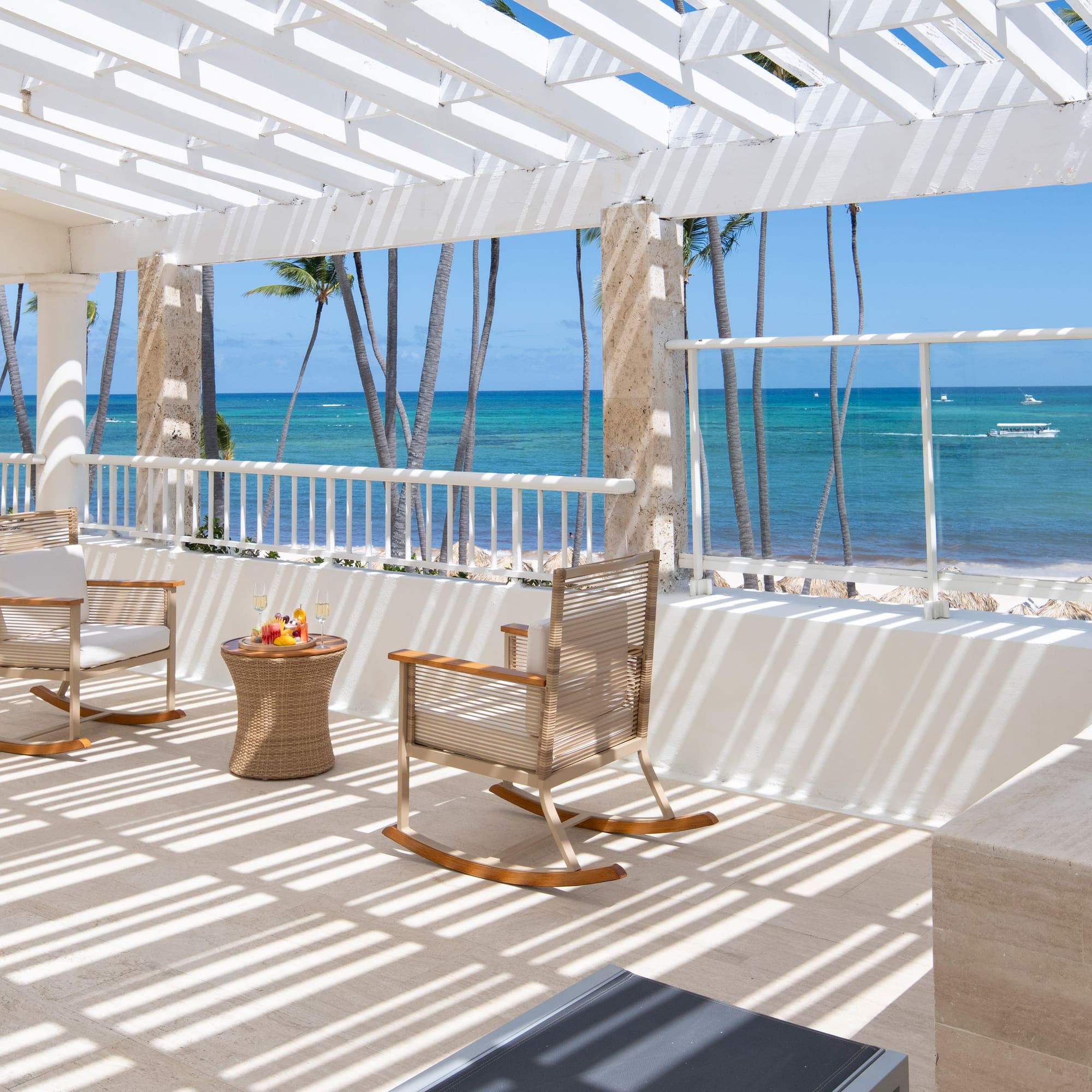 a patio with chairs and a table on a beach
