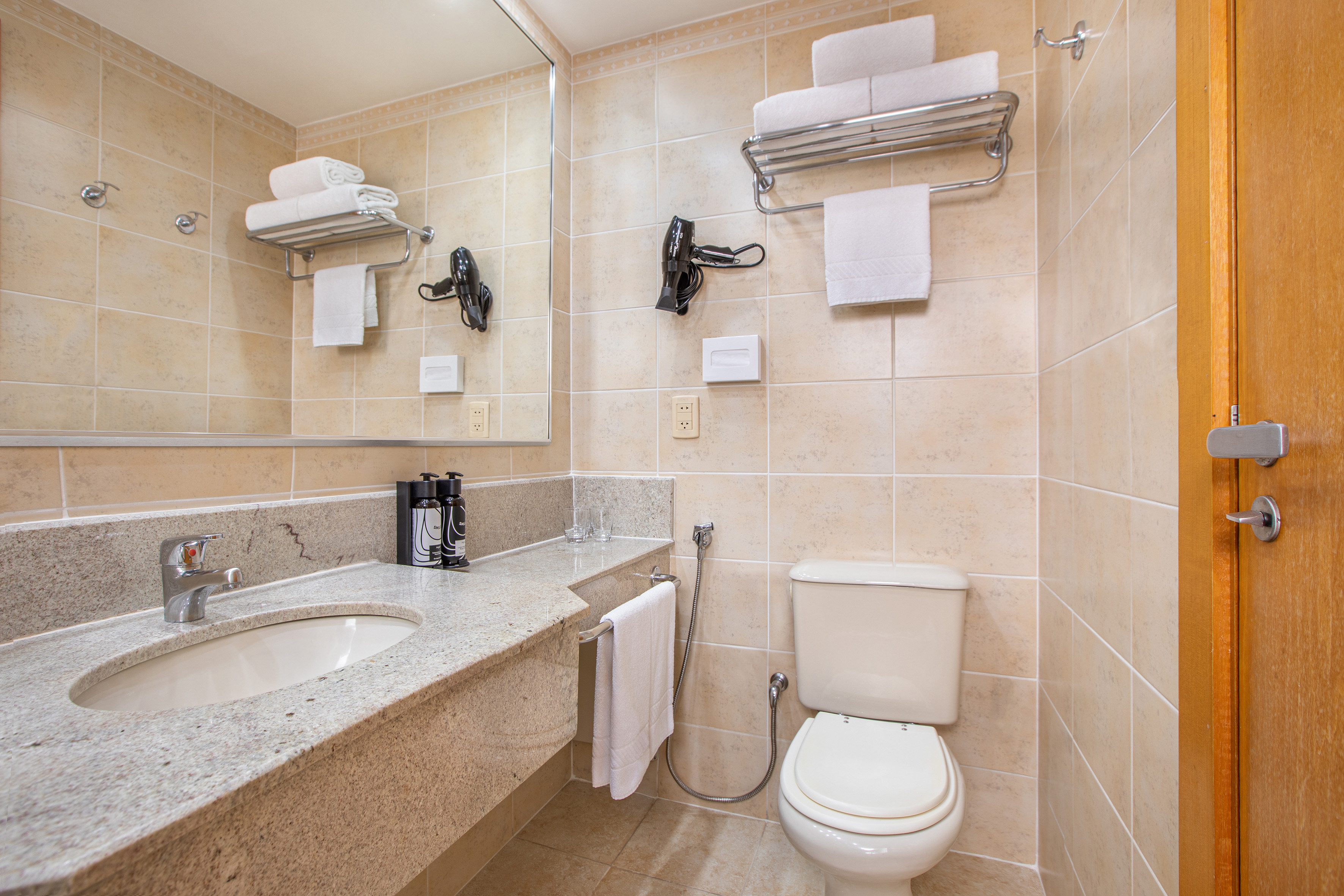 Hotel bathroom with granite vanity, sink, toilet, bidet, and white towels.