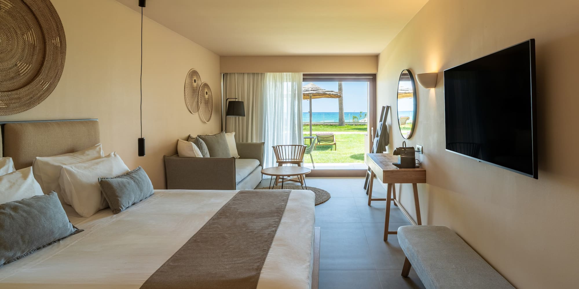 Luxury hotel suite with bed, sofa, and stunning ocean view terrace.