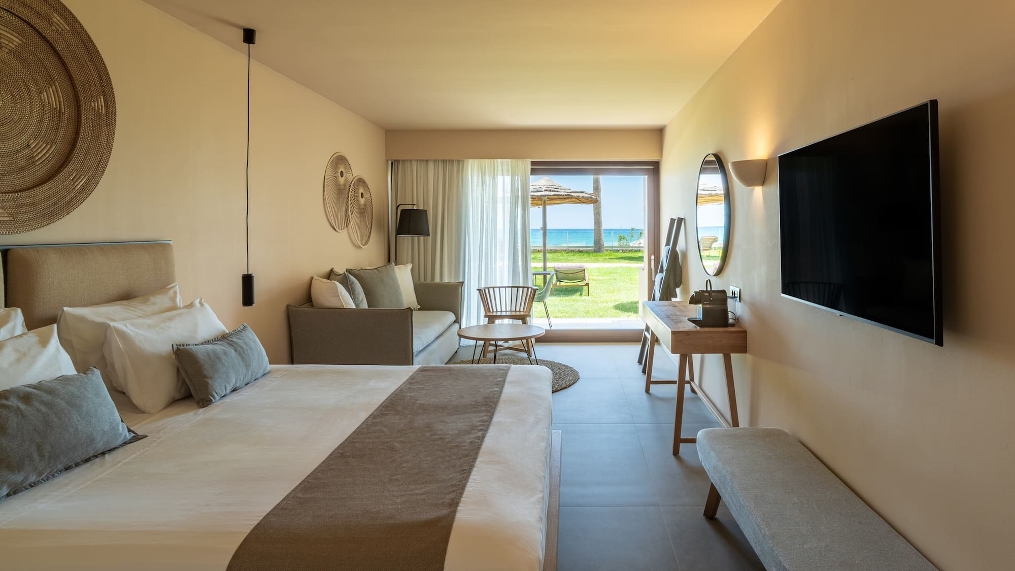 Luxury hotel room with king bed, sofa, and ocean view patio.