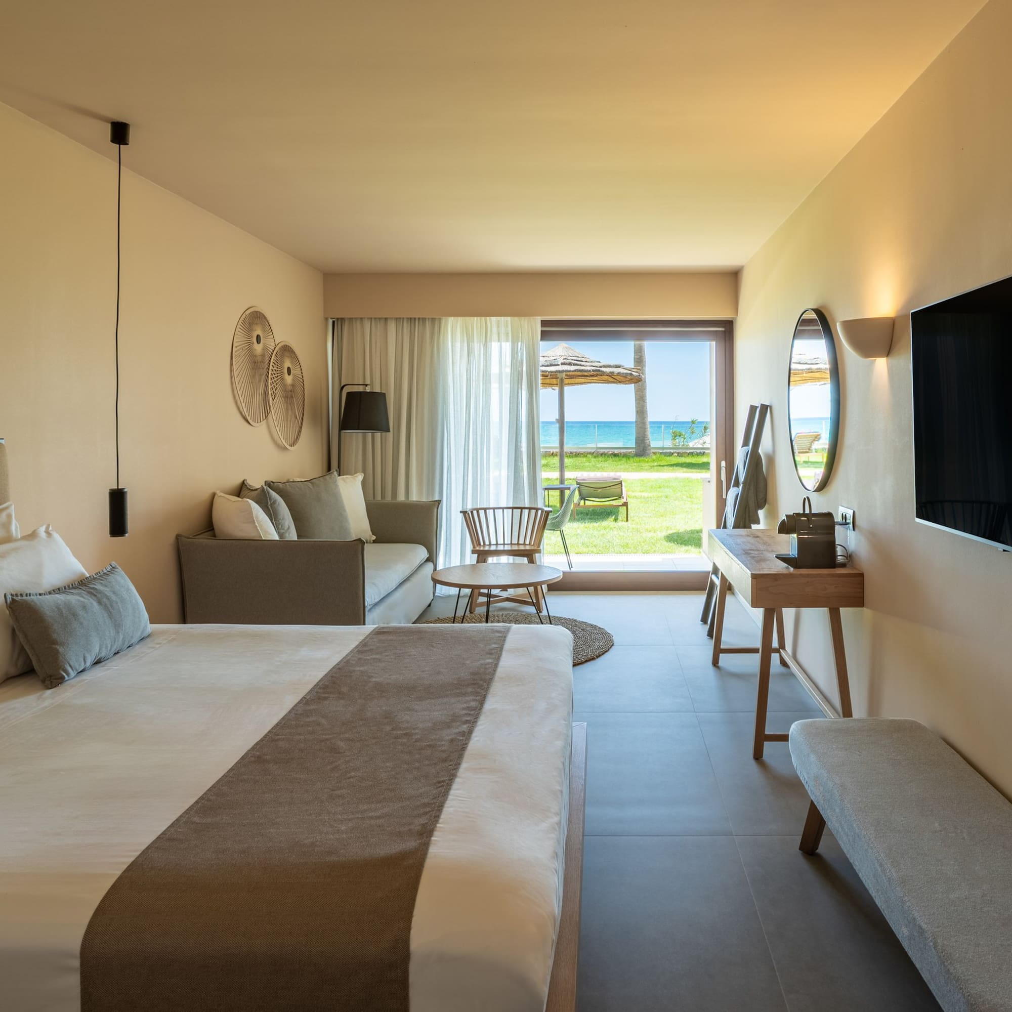 Luxury hotel room with king bed, sofa, and ocean view patio.