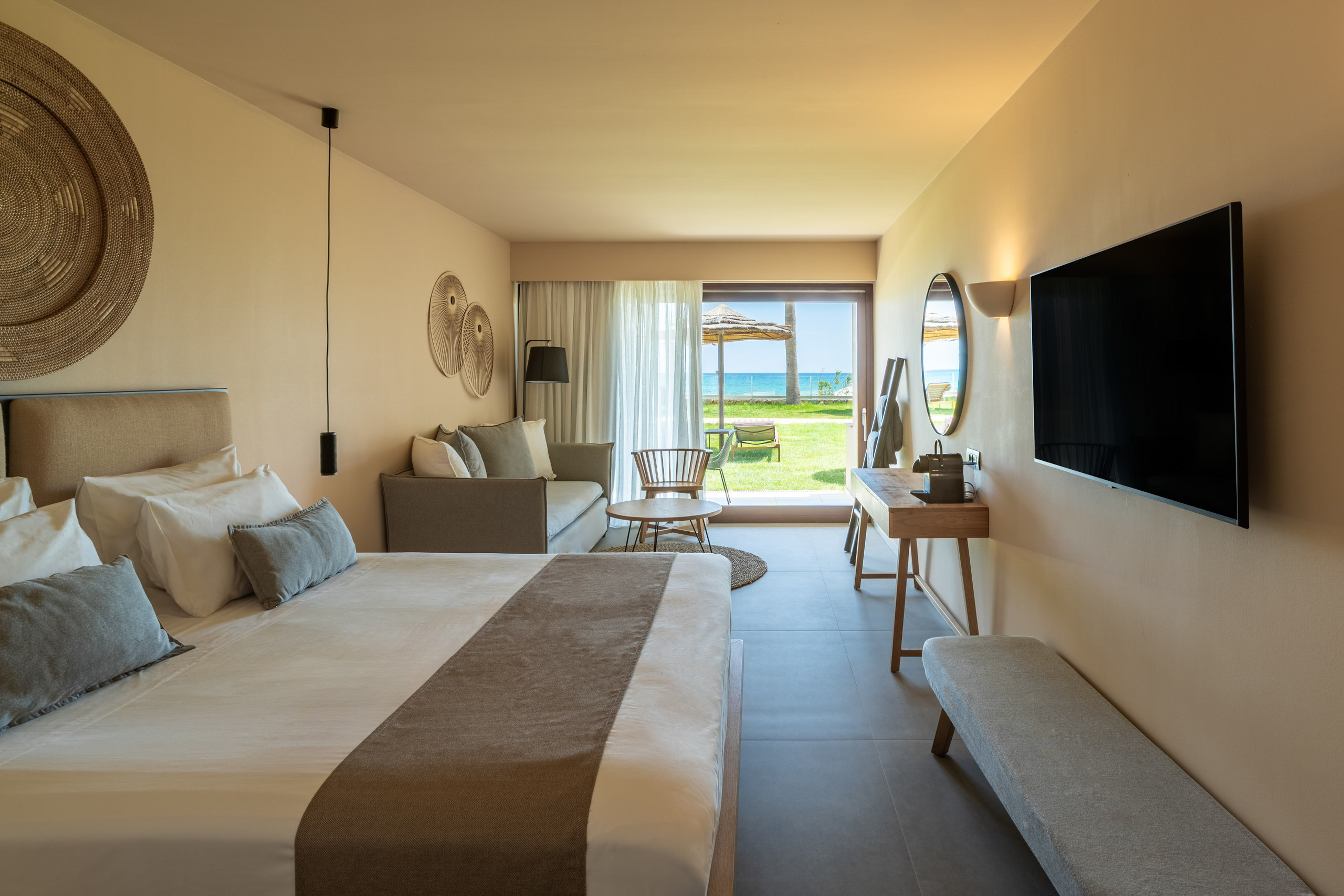 Luxury hotel room with king bed, sofa, and ocean view patio.