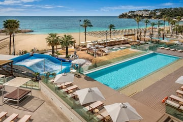 a pool and beach with umbrellas and chairs