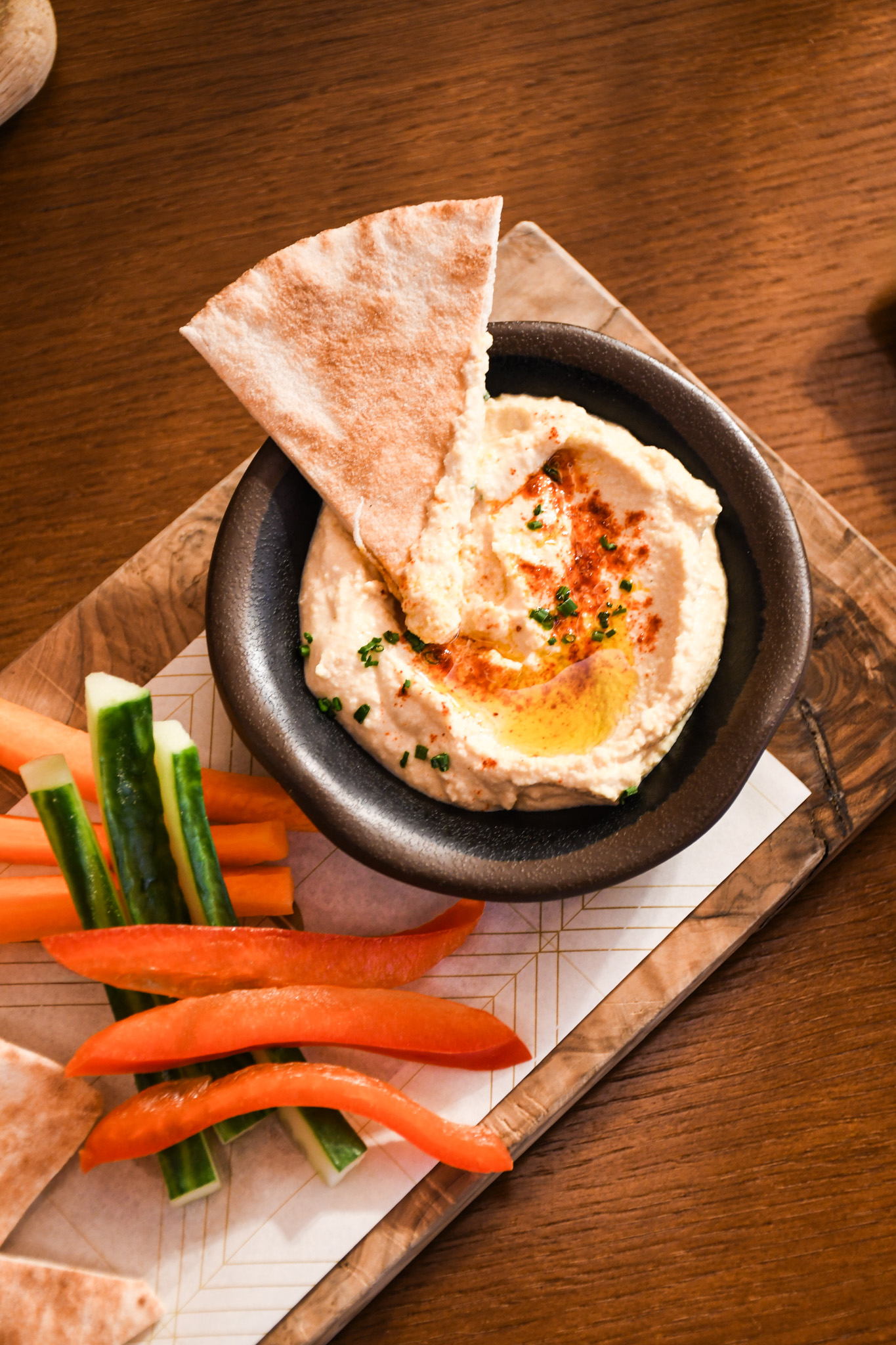 Hummus dip with pita bread, carrots, cucumber, and bell pepper sticks.