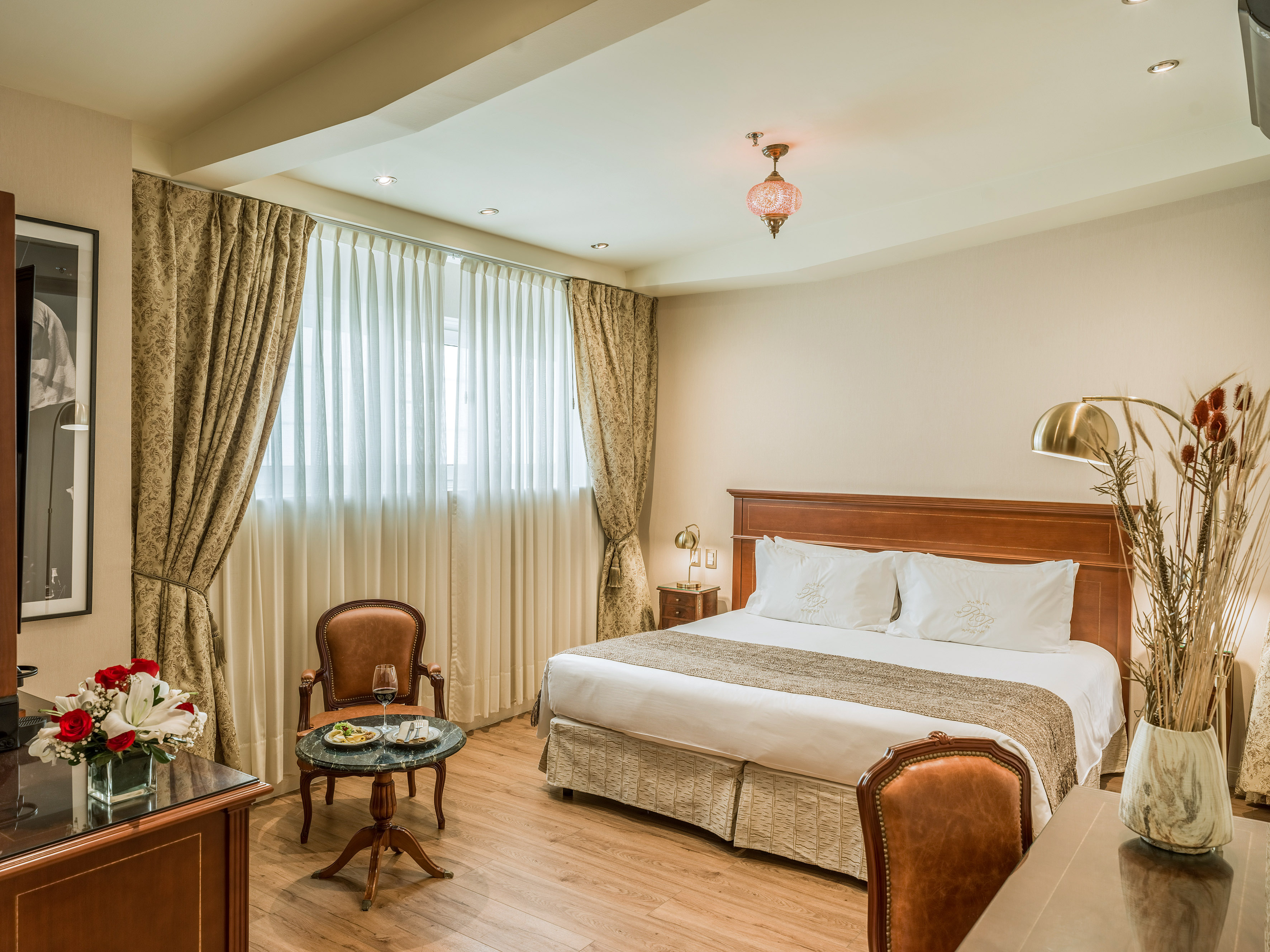 Luxurious hotel room featuring a large bed, seating area, and elegant decor.