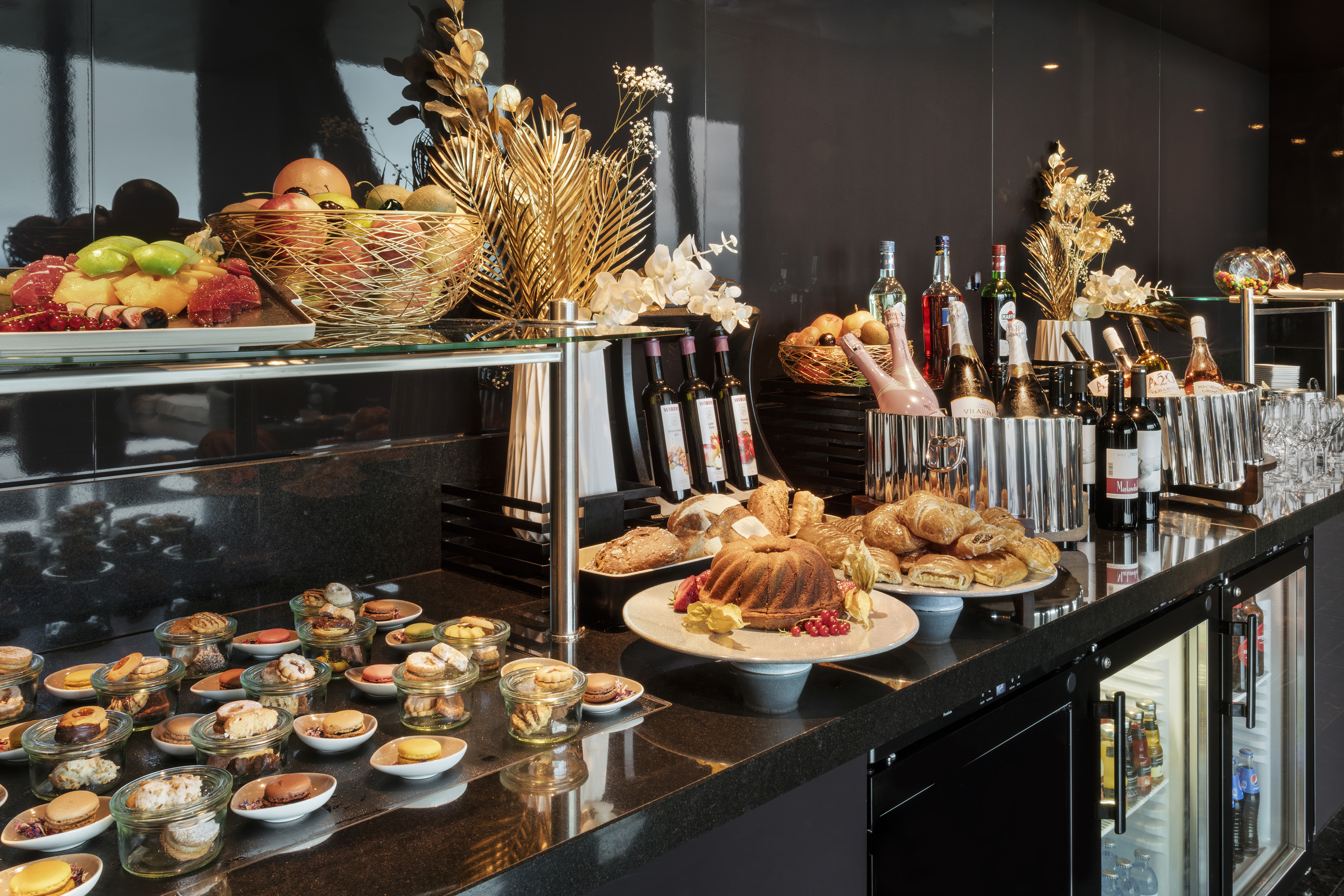 Gourmet buffet with fresh fruit, assorted pastries, wine, and sparkling beverages.