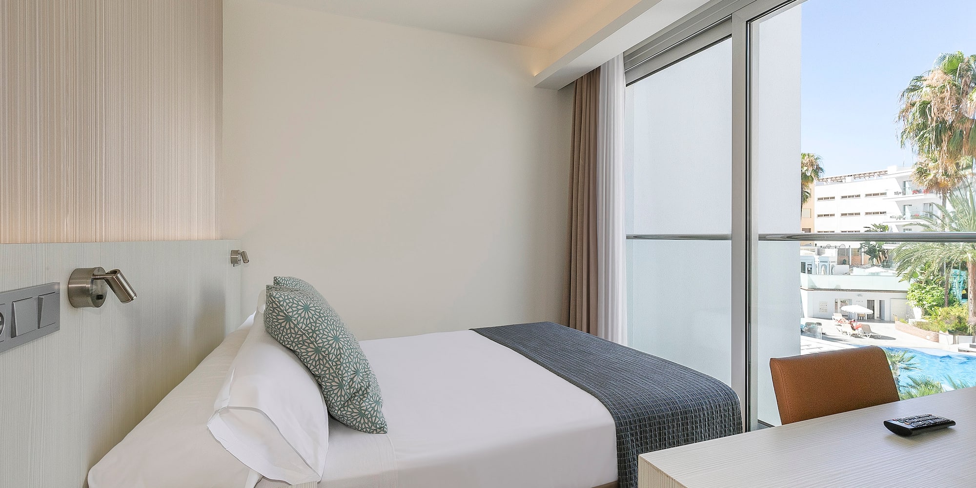 a bed and desk in a room with glass doors