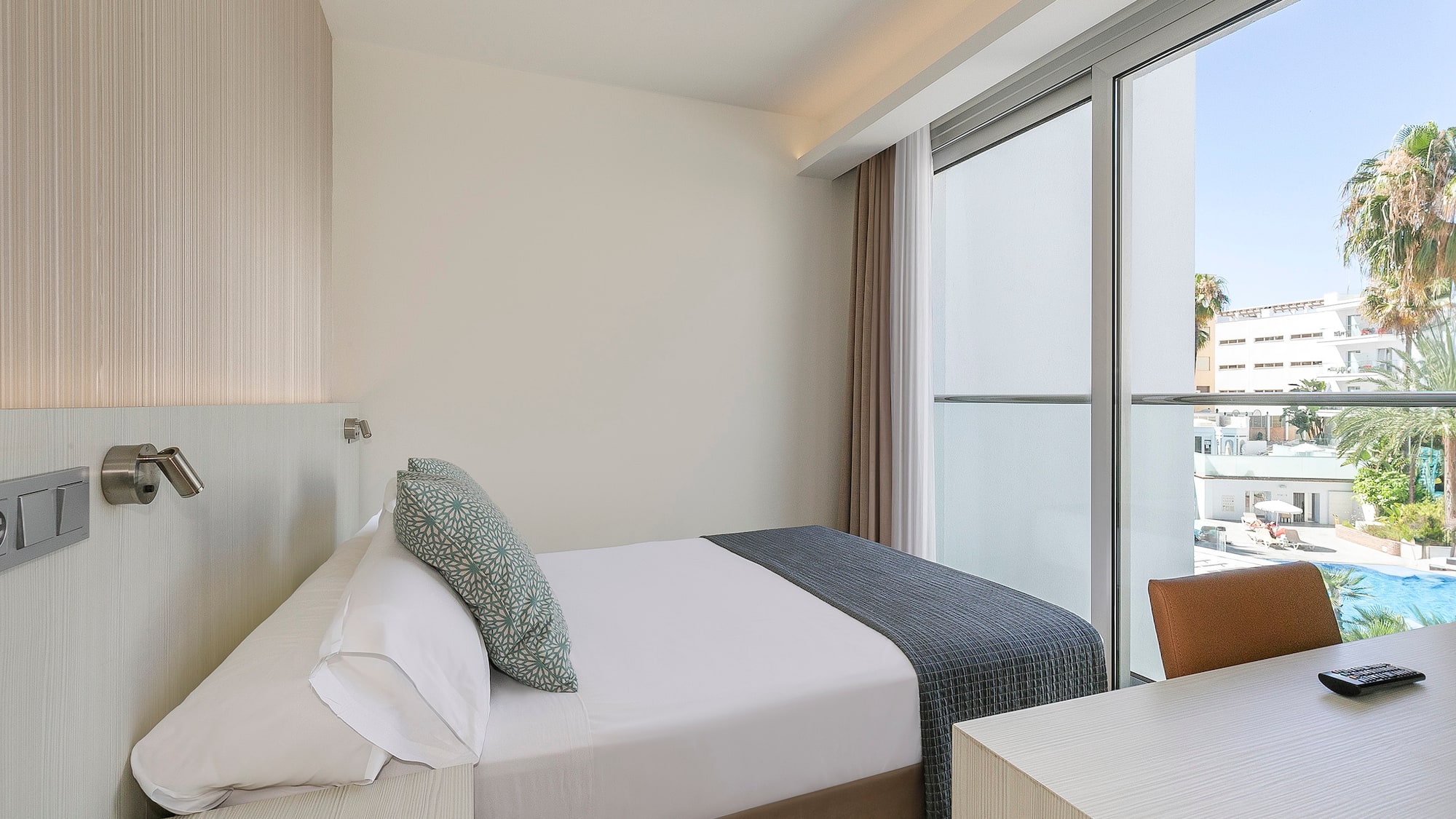 a bed and desk in a room with glass doors