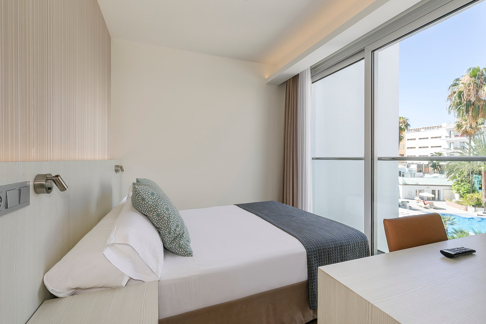 a bed and desk in a room with glass doors