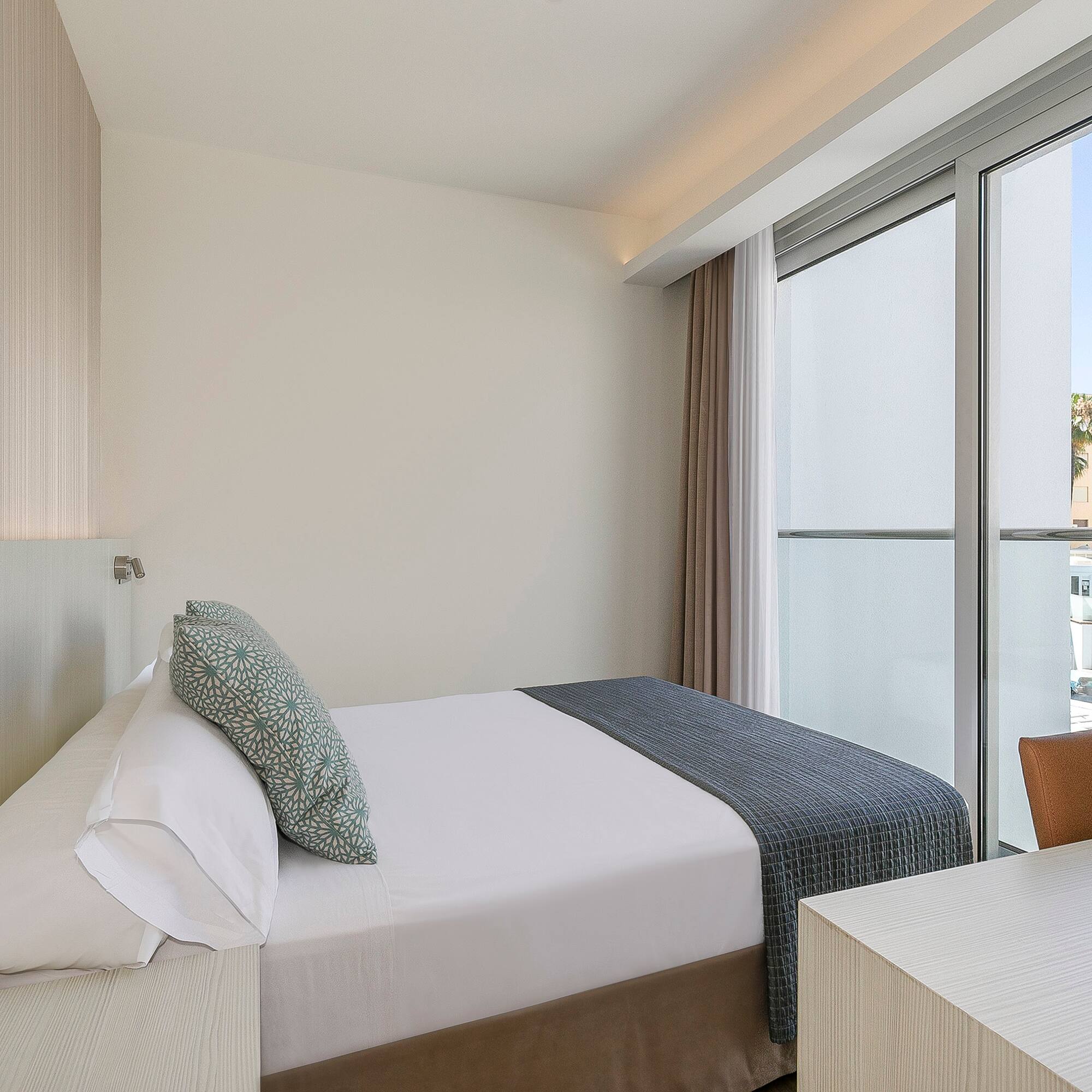 a bed and desk in a room with glass doors