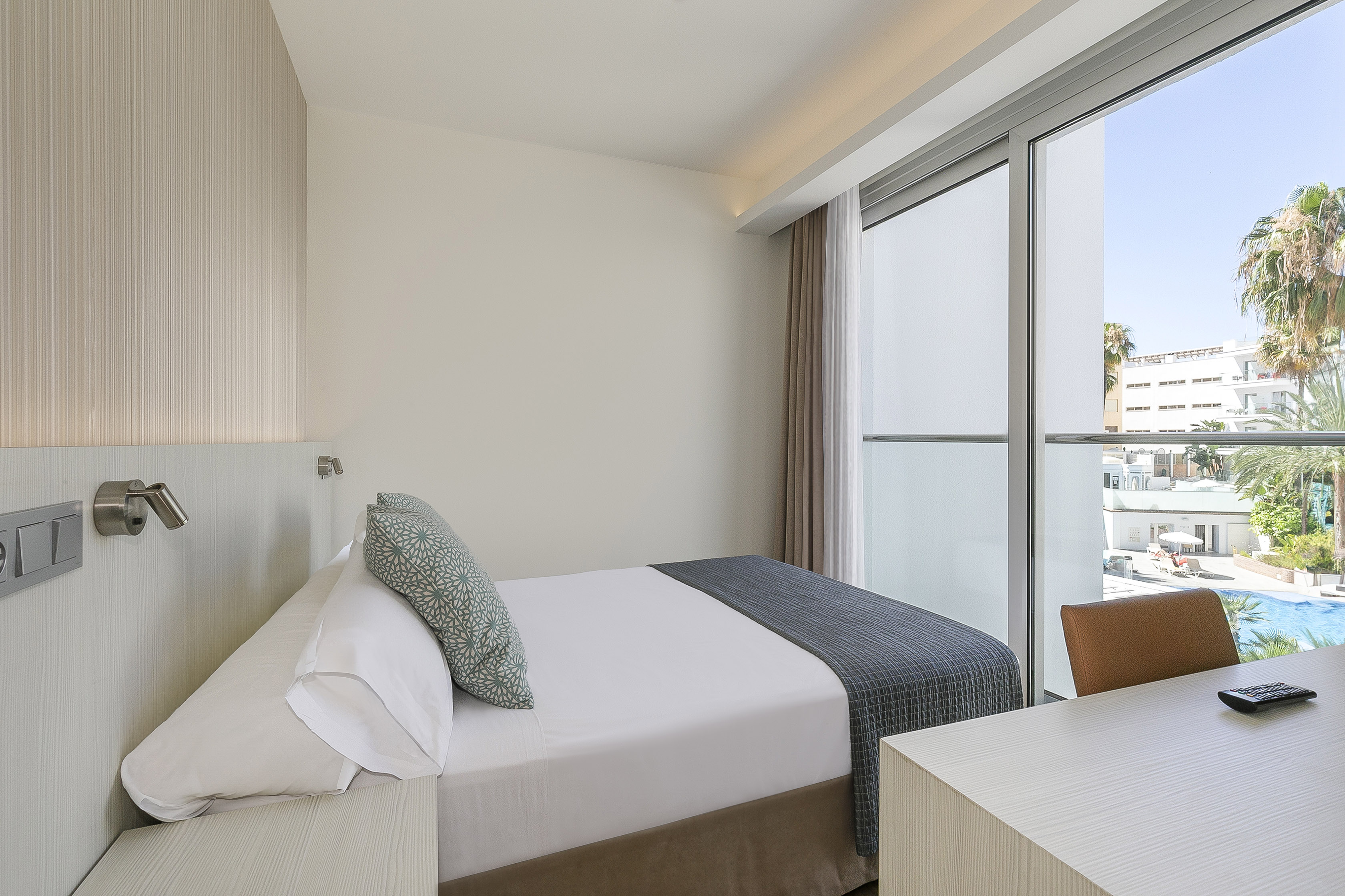 a bed and desk in a room with glass doors