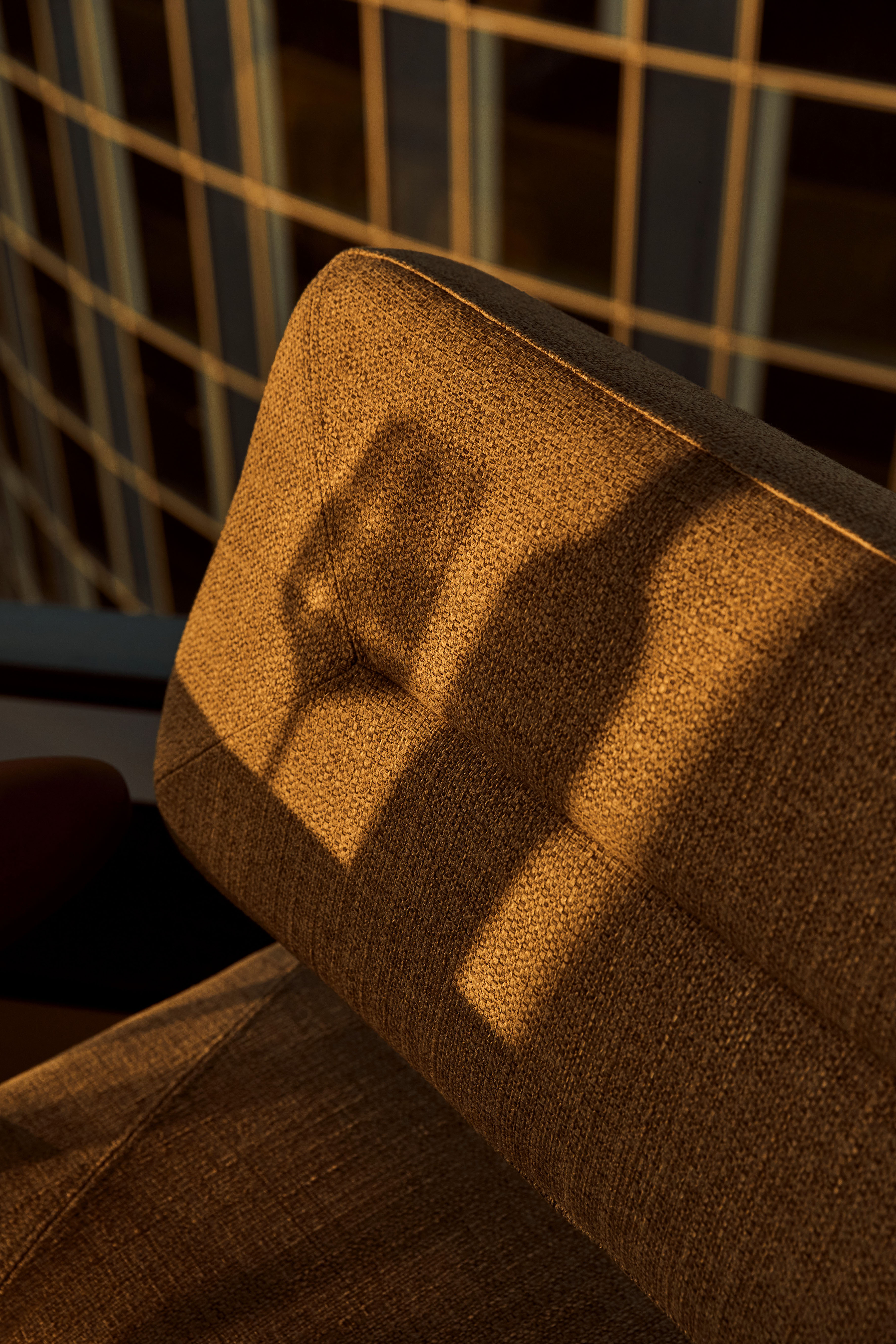 Golden hour light on brown sofa, casting wine glass and bottle shadows.
