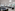 Empty conference room with tables, chairs, projector screen, and bright windows.
