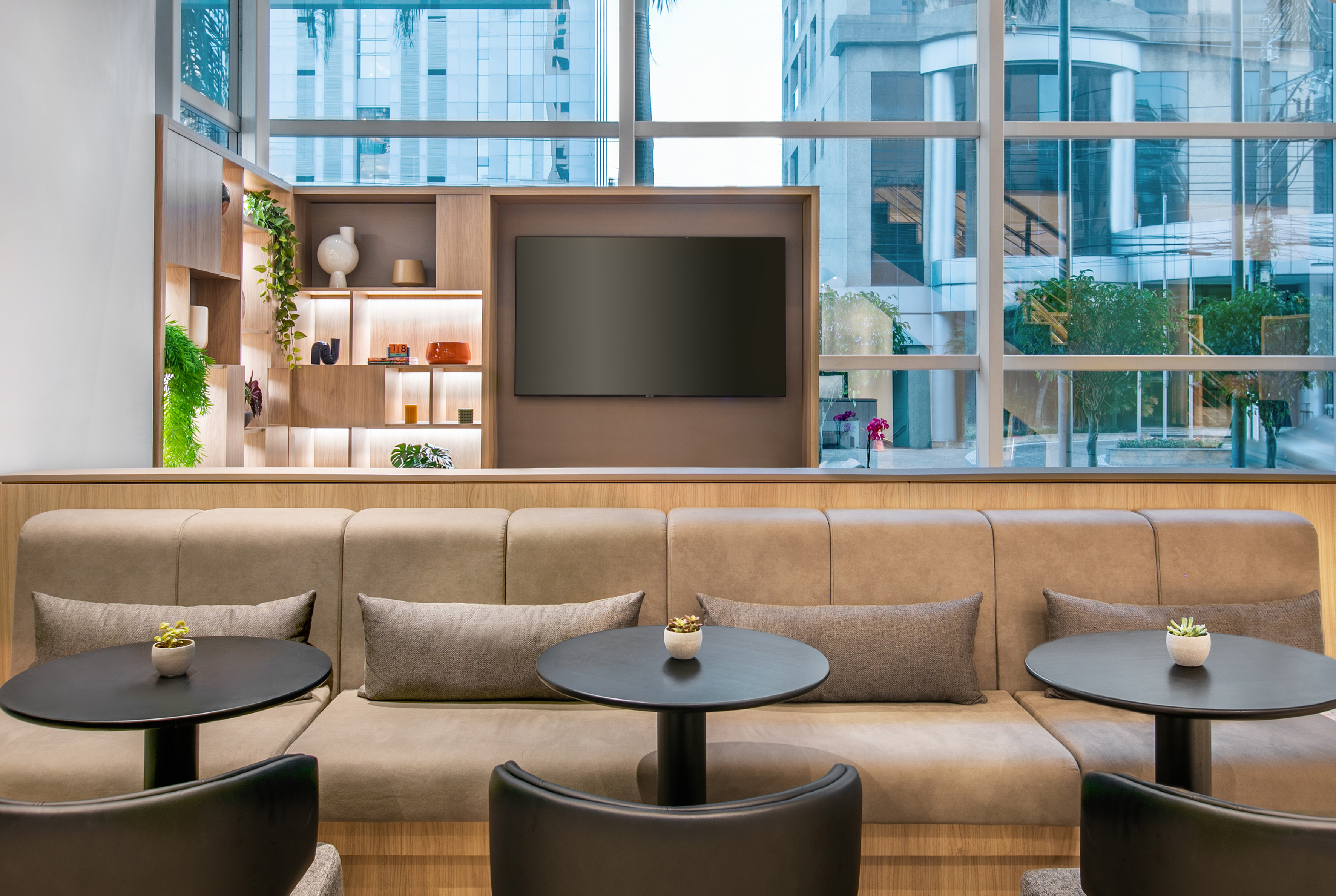 Modern lounge with built-in seating, TV, shelves, and city window view.