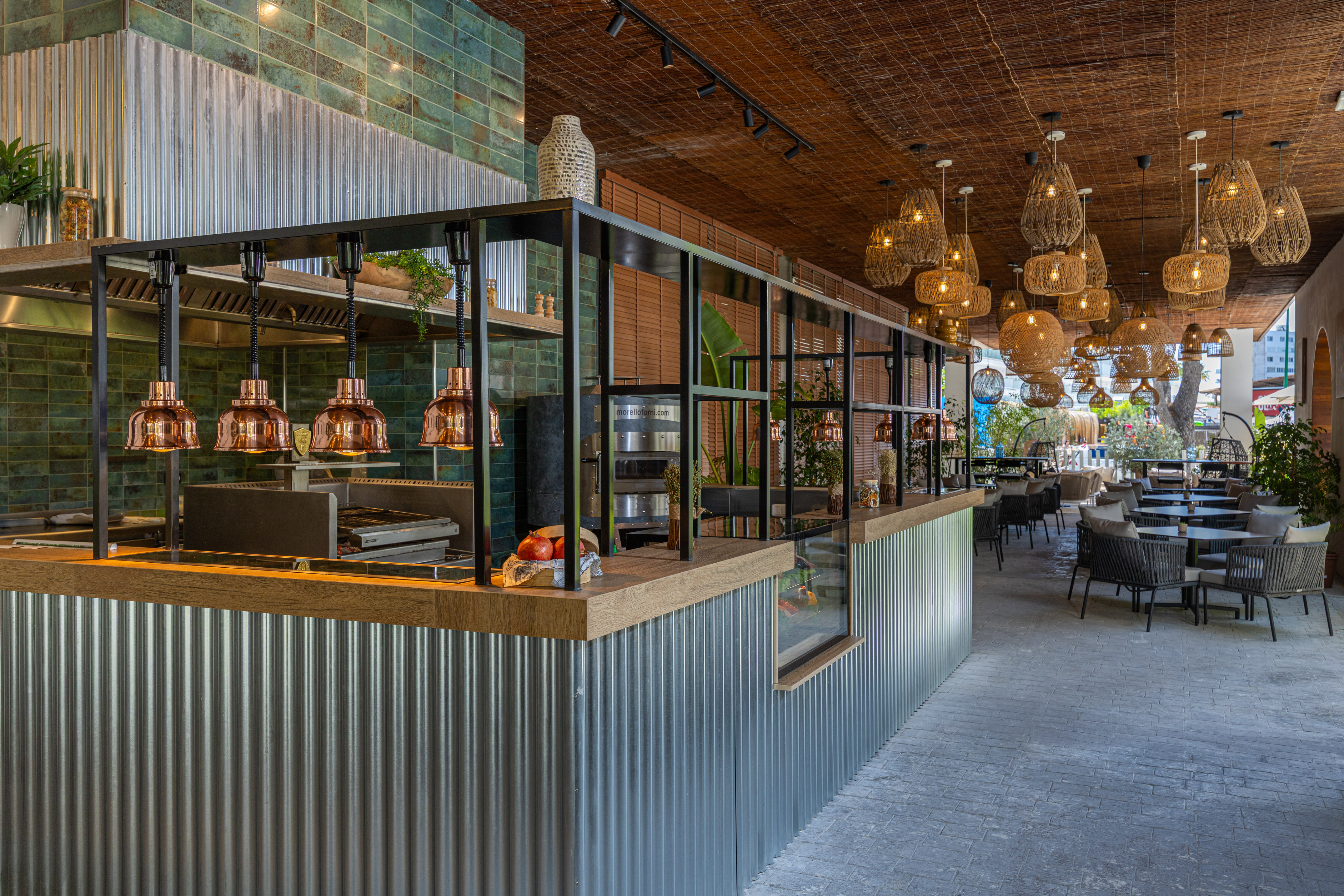 Modern restaurant with corrugated bar, green tiles, and rustic lighting.