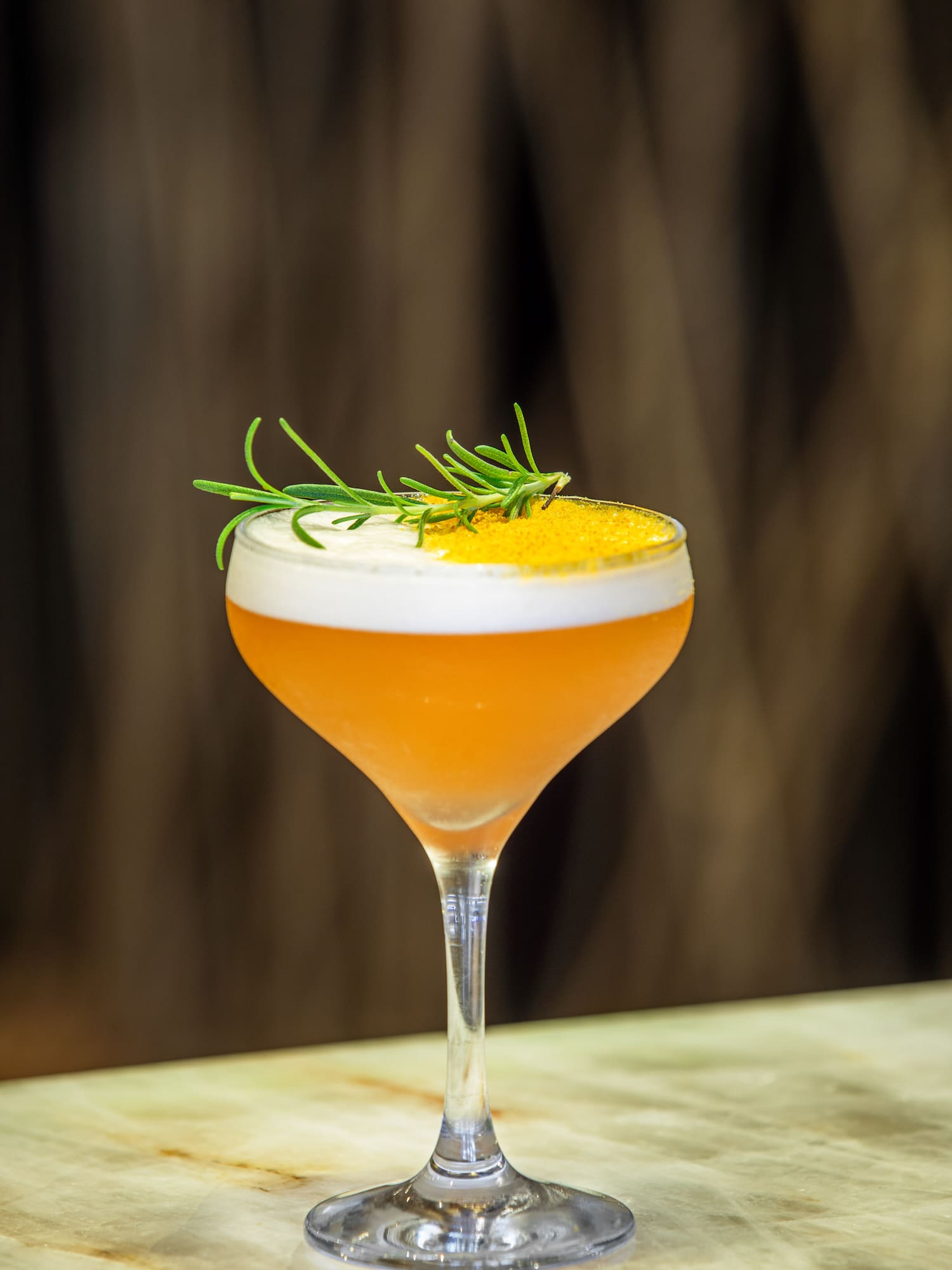 a glass with a drink and a sprig of rosemary