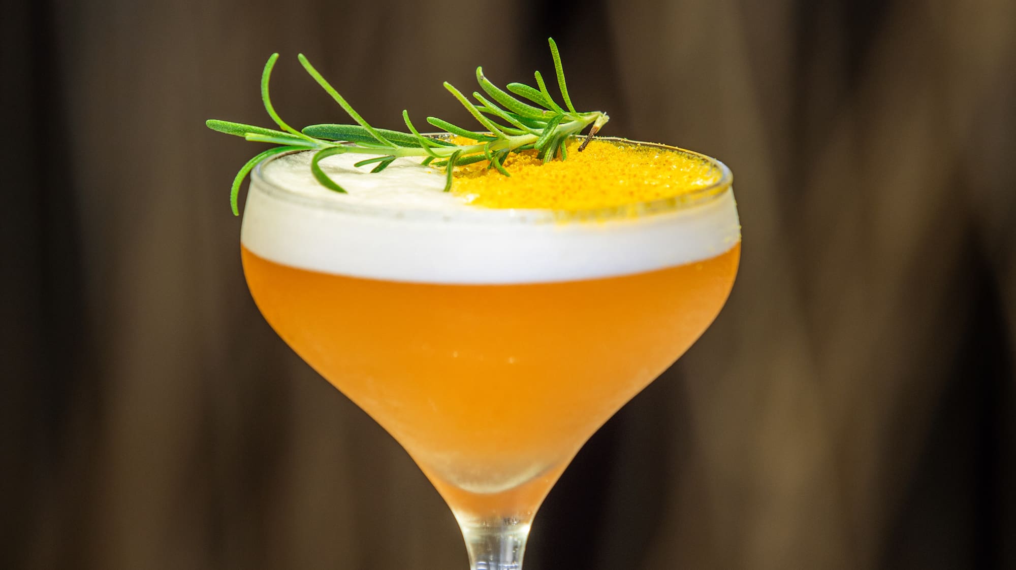 a glass with a drink and a sprig of rosemary