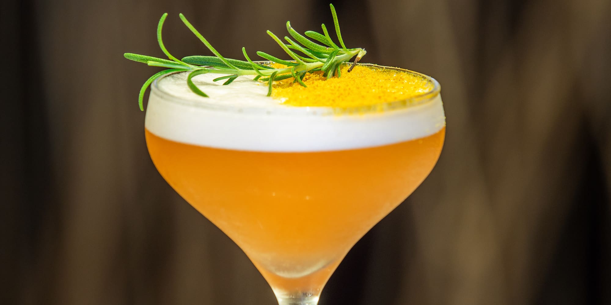 a glass with a drink and a sprig of rosemary
