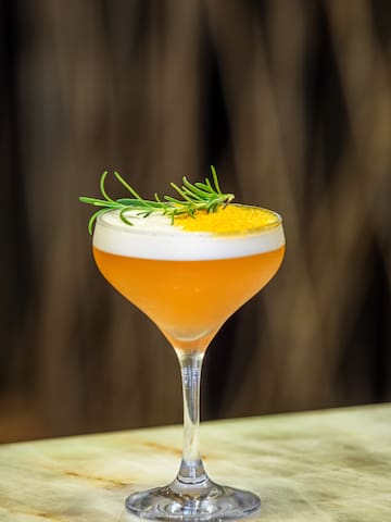 a glass with a drink and a sprig of rosemary