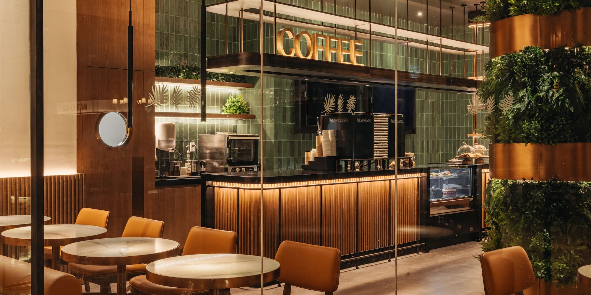 Modern cafe with illuminated COFFEE sign, green tiles, and wood accents.