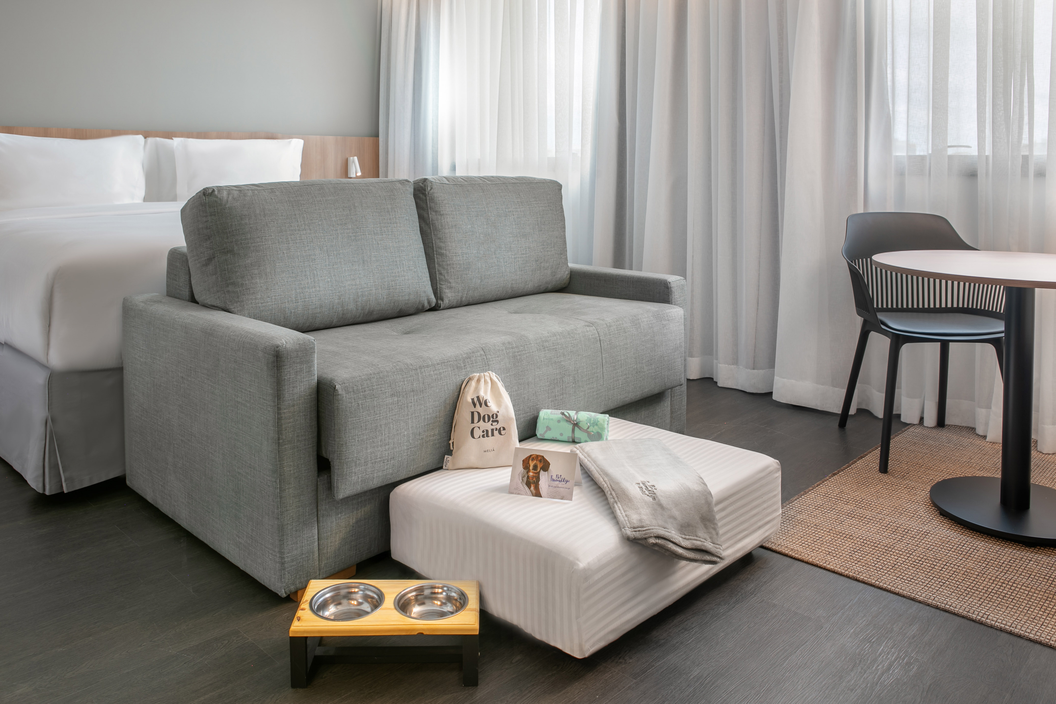 Pet-friendly hotel room with sofa bed, dog bowls, and pet care amenities.