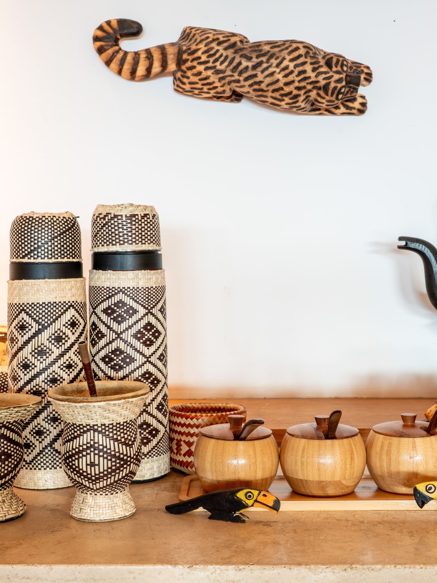 Mate gourds, woven thermoses, kettle, snacks, and a wooden jaguar carving.