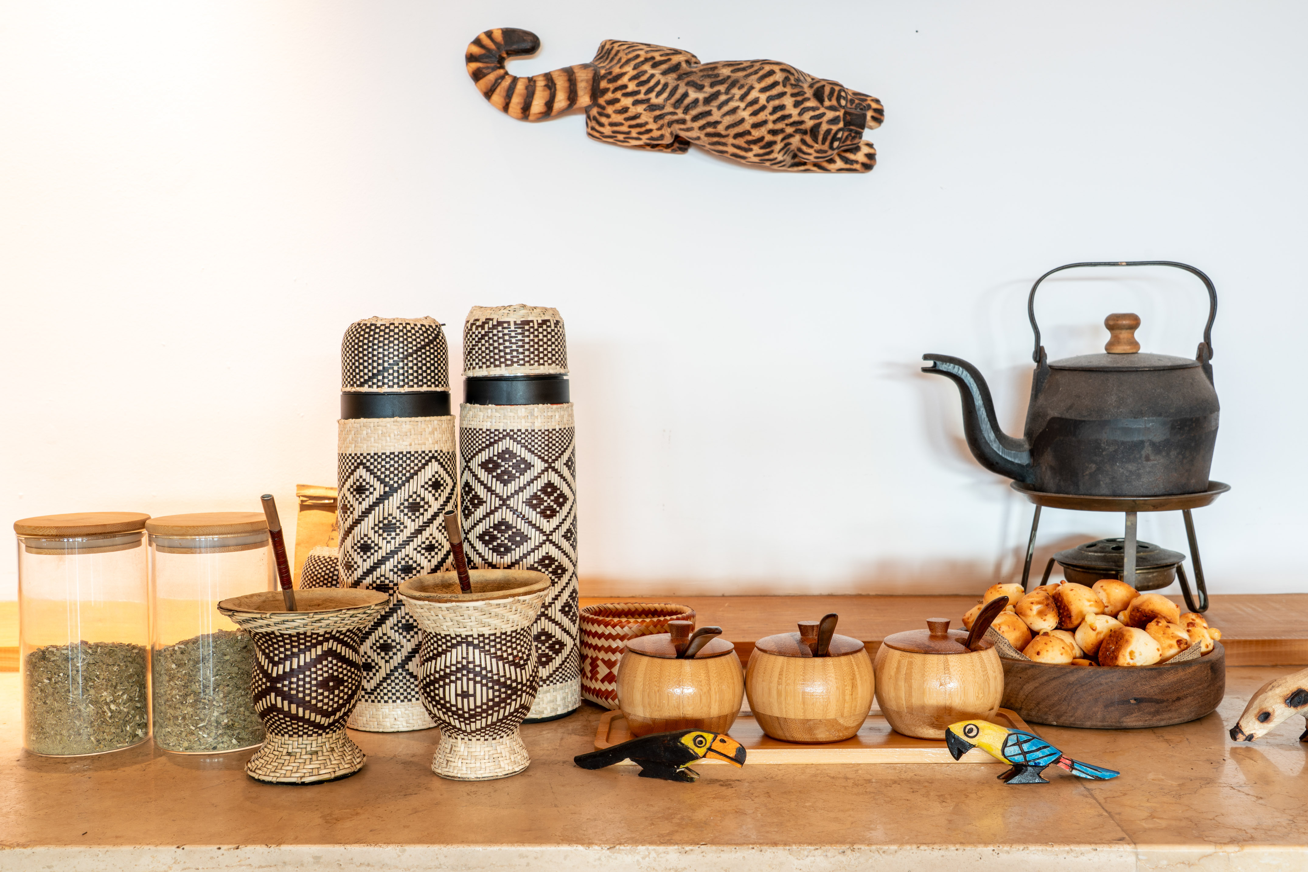 Mate gourds, woven thermoses, kettle, snacks, and a wooden jaguar carving.