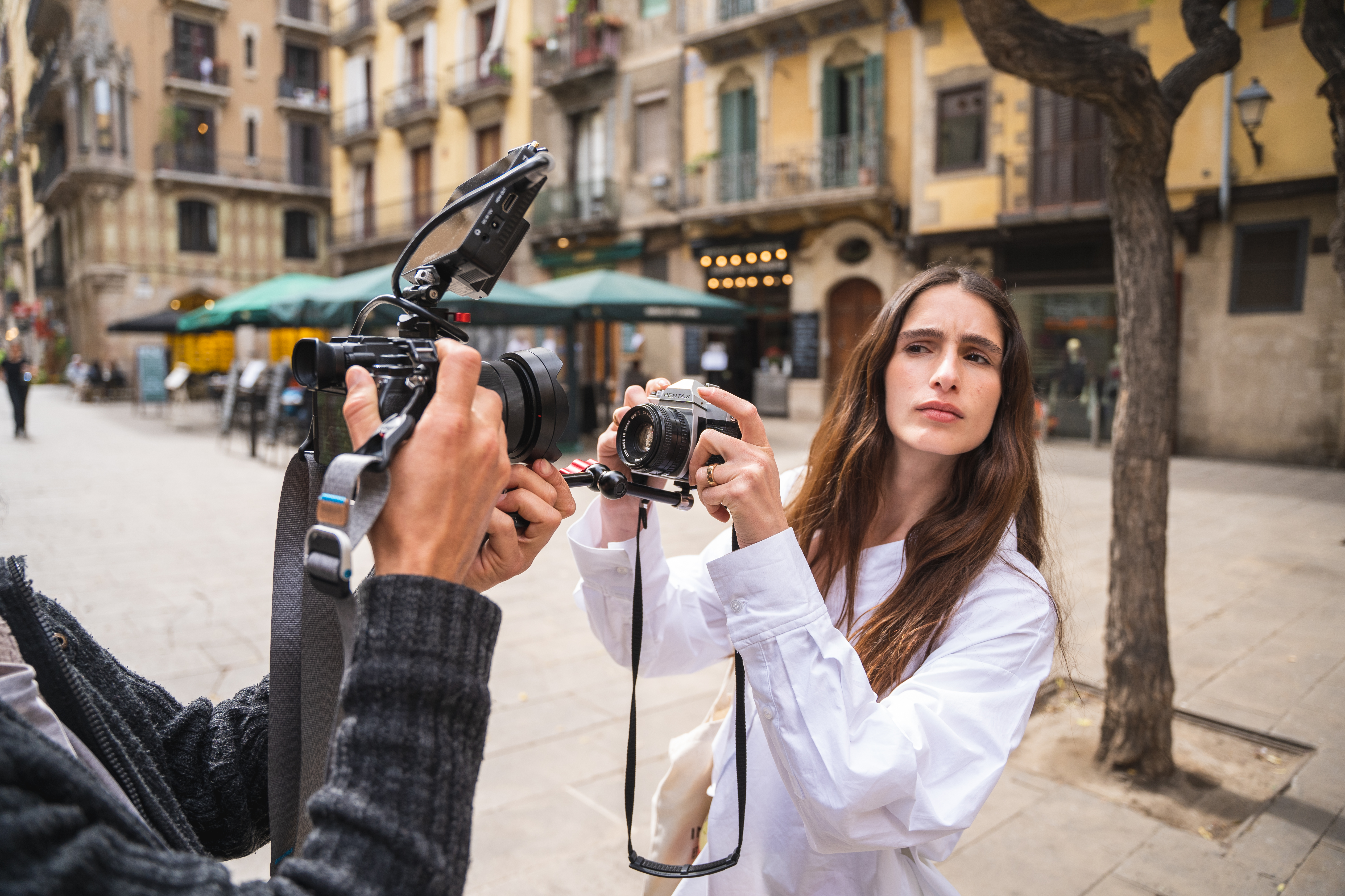 Mujer con cámara Pentax vintage y hombre con videocámara en calle de Barcelona.