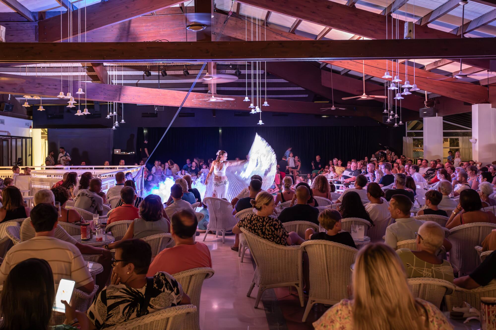 Live resort entertainment: dancer performs with shimmering fans for a seated audience.