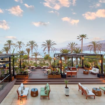 a deck with chairs and tables and palm trees