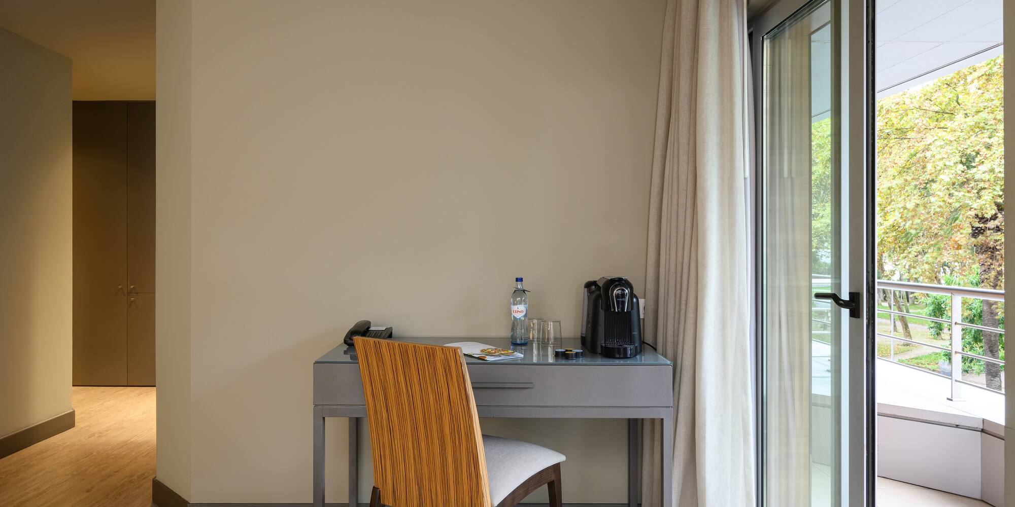 a desk with a chair and a bottle of water in front of a glass door