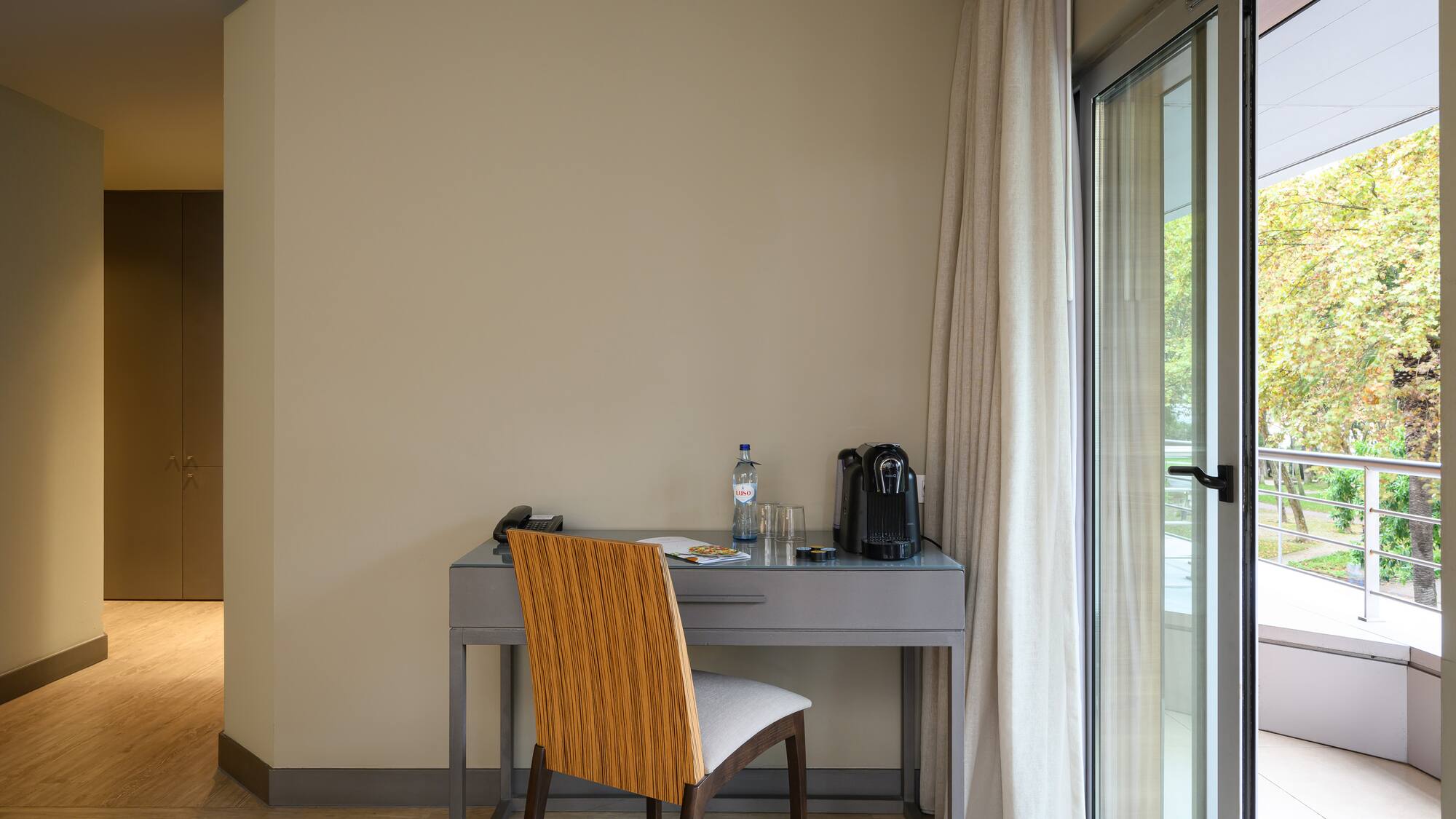 a desk with a chair and a bottle of water in front of a glass door