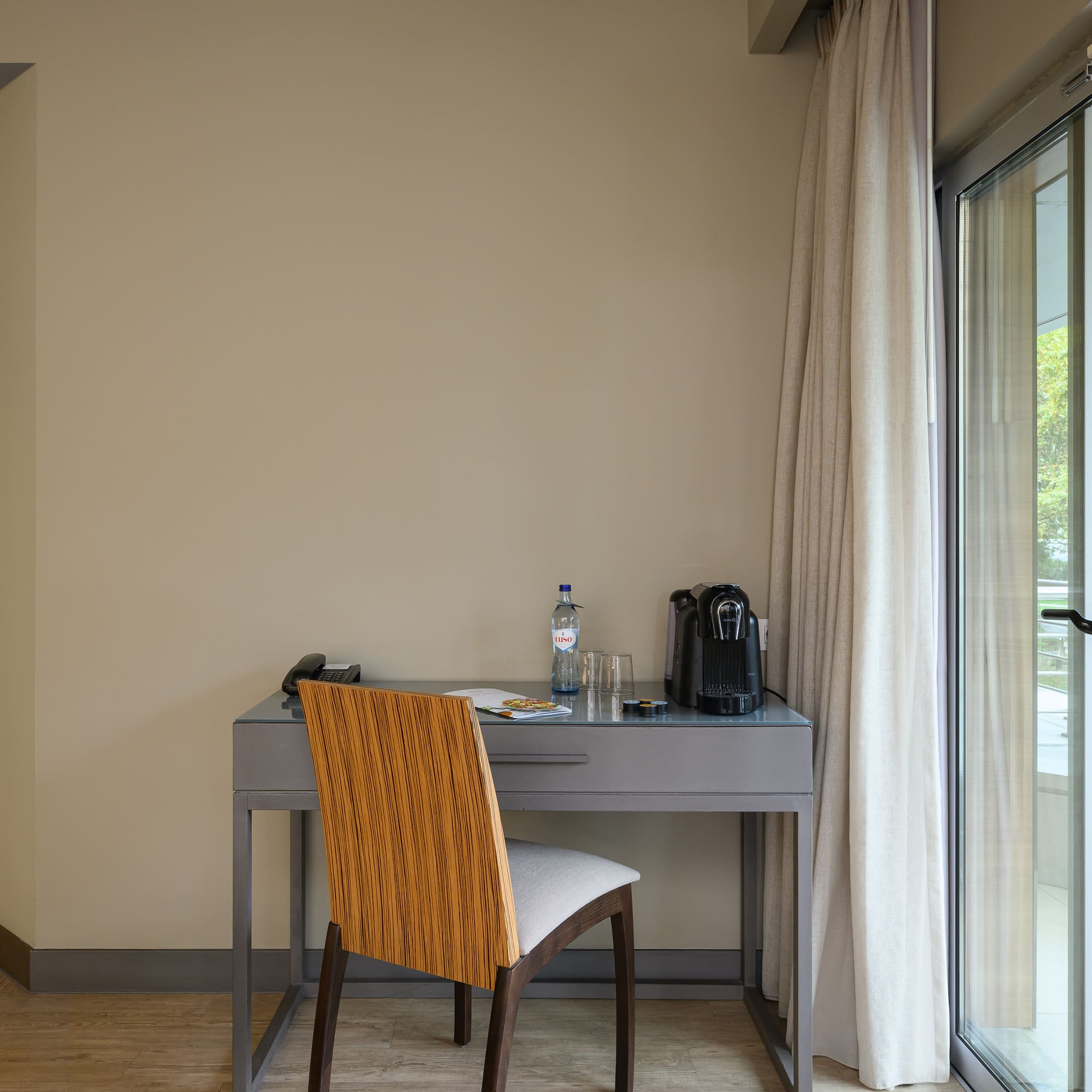a desk with a chair and a bottle of water in front of a glass door