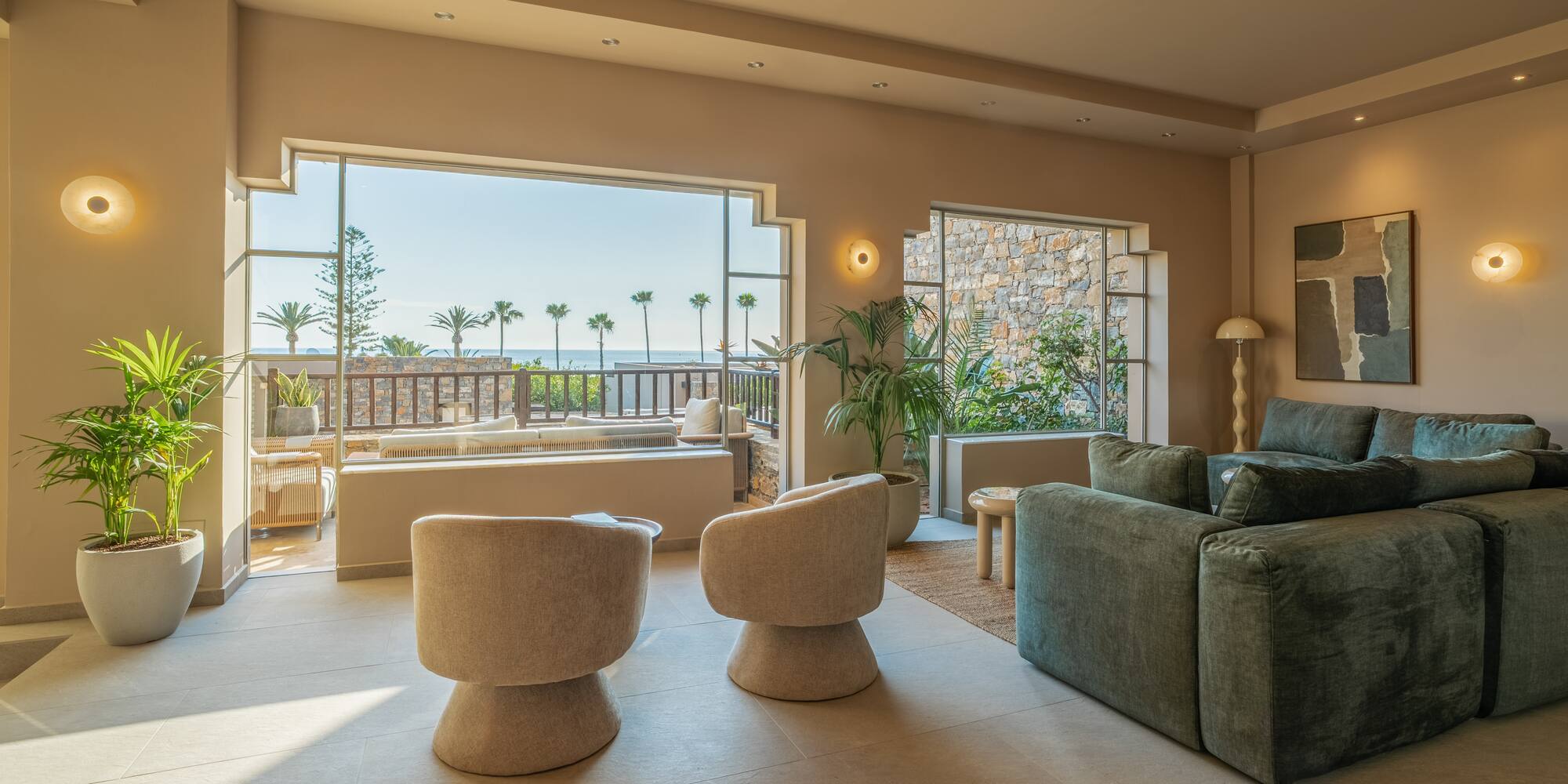 Luxury living room with ocean view, palm trees, modern sofa, and armchairs.