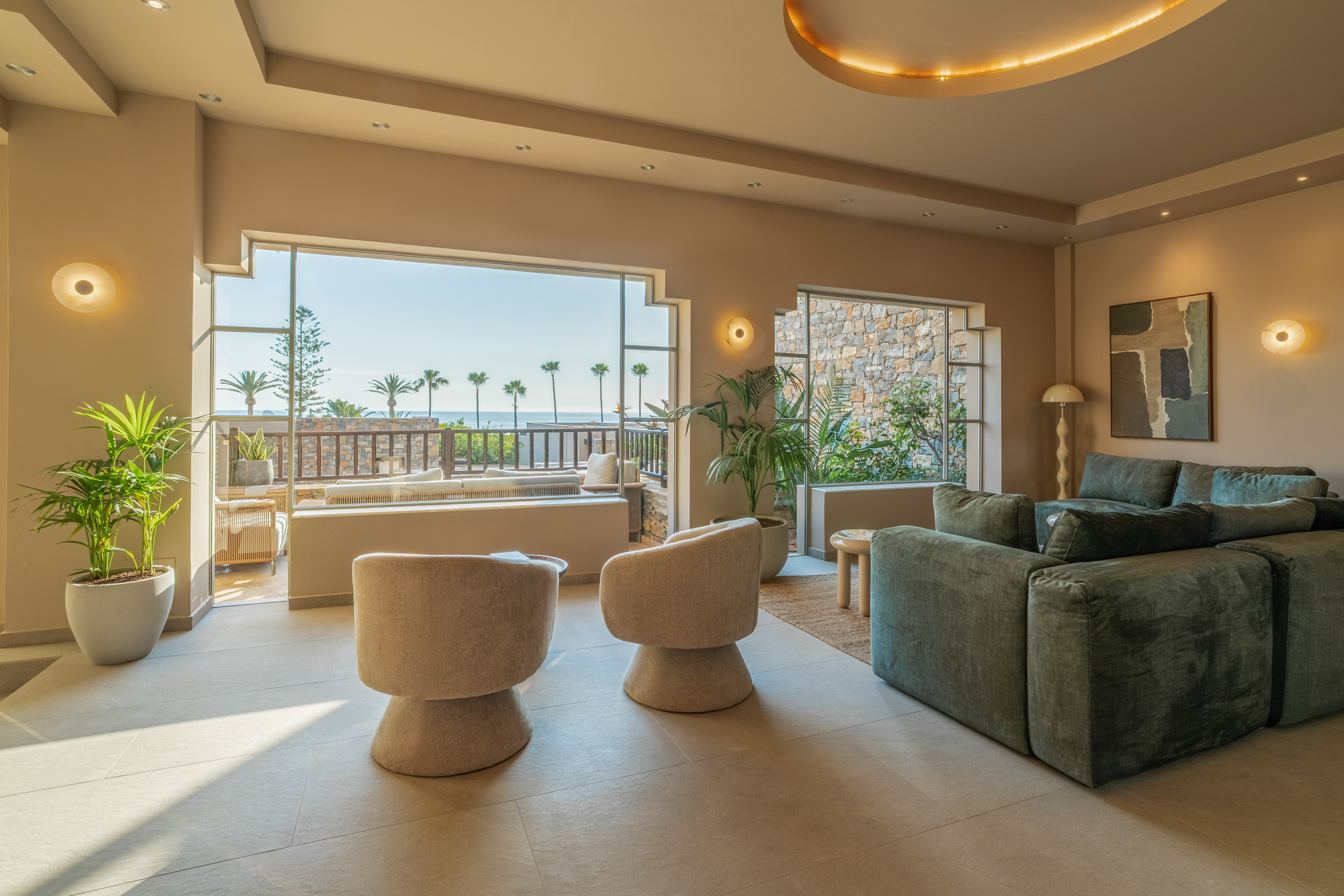 Luxury living room with ocean view, palm trees, modern sofa, and armchairs.