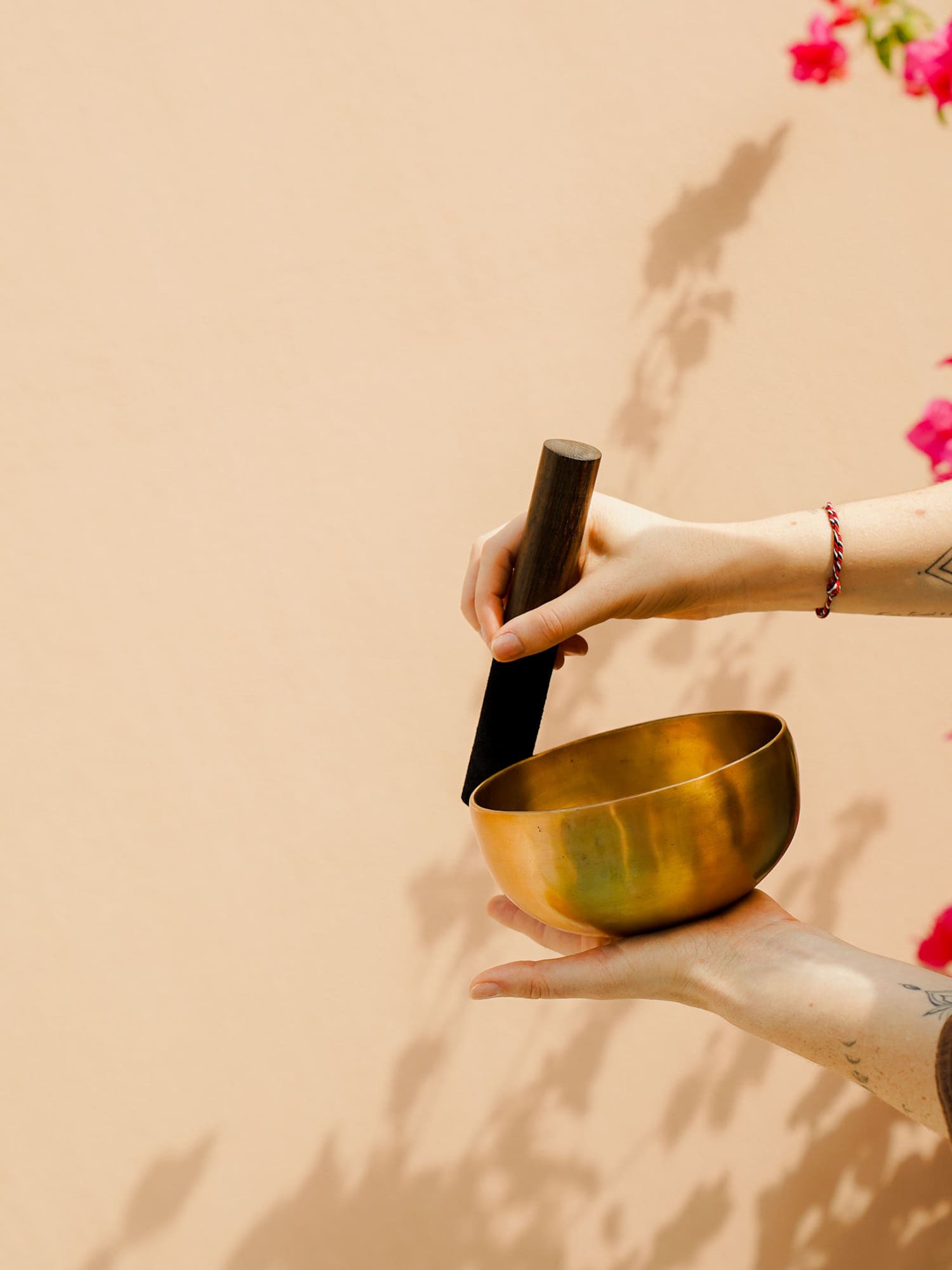 Sound healing: Hands holding a brass singing bowl and mallet.