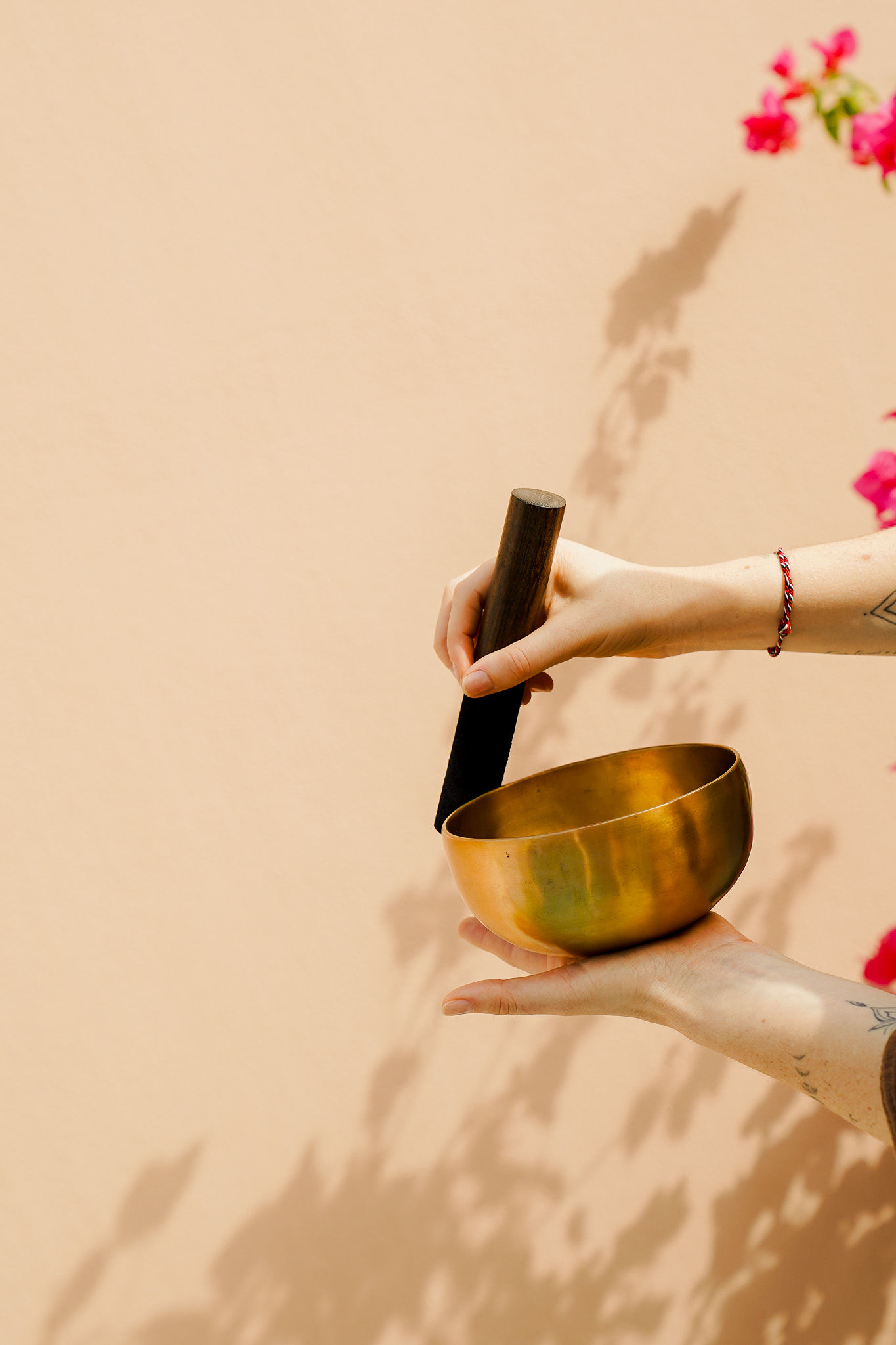 Sound healing: Hands holding a brass singing bowl and mallet.