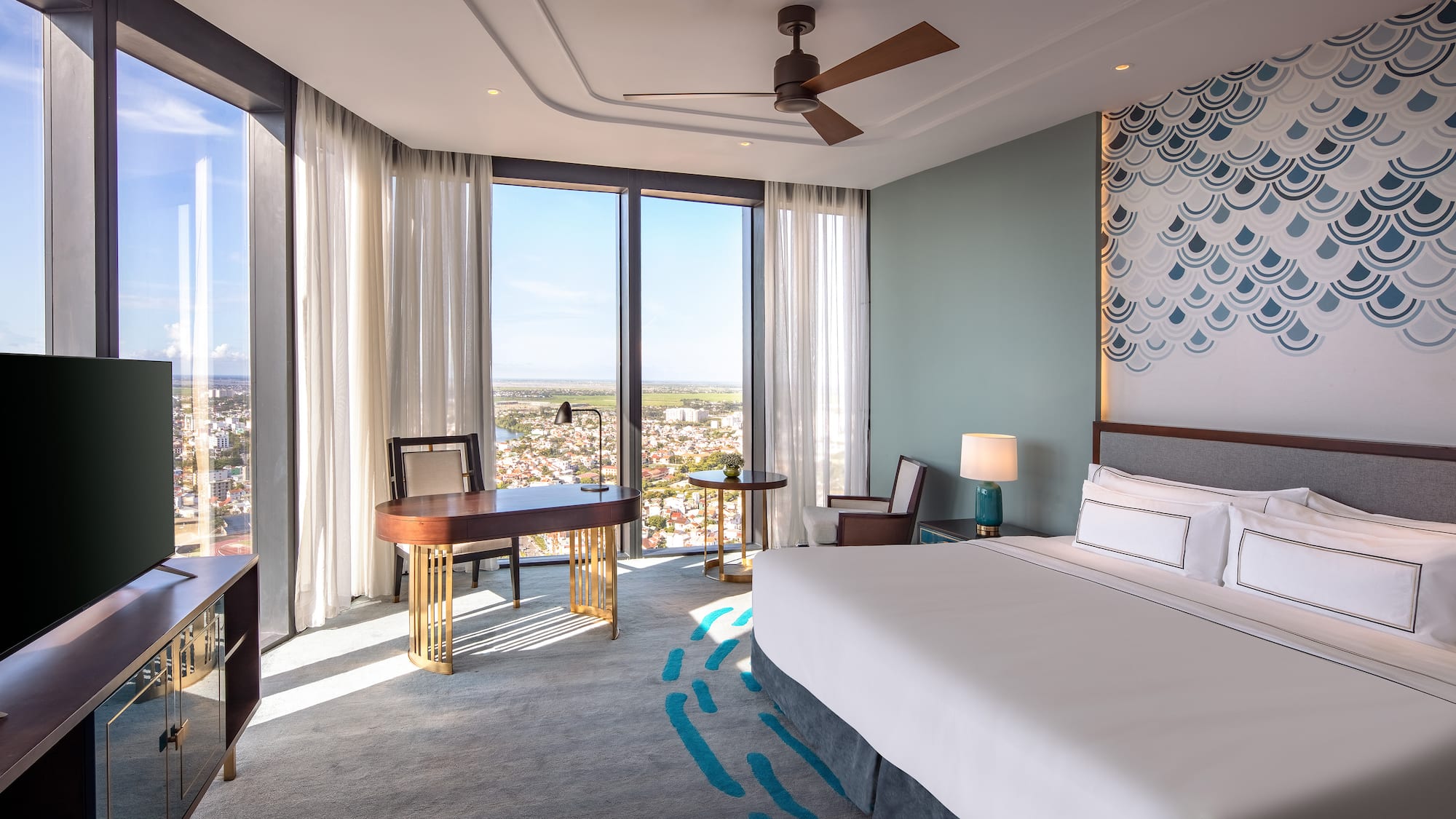 a room with a bed and a desk and a fan