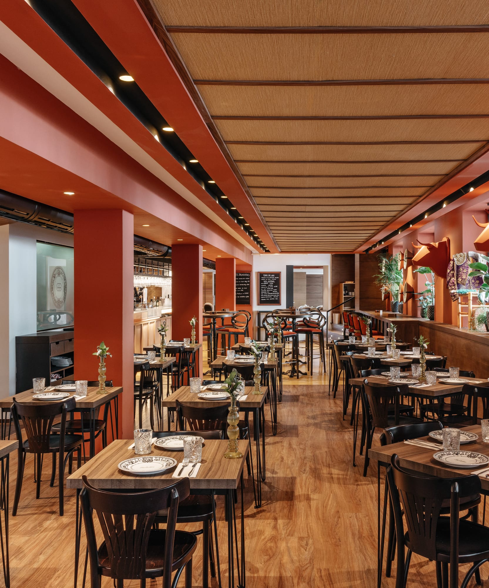 Comedor de restaurante con mesas de madera, paredes naranjas y cabezas de toro.