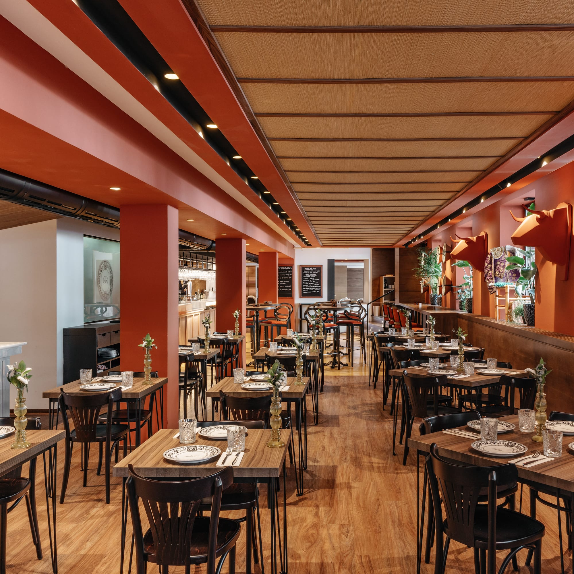 Restaurante con diseño naranja, mesas de madera y decoración taurina.