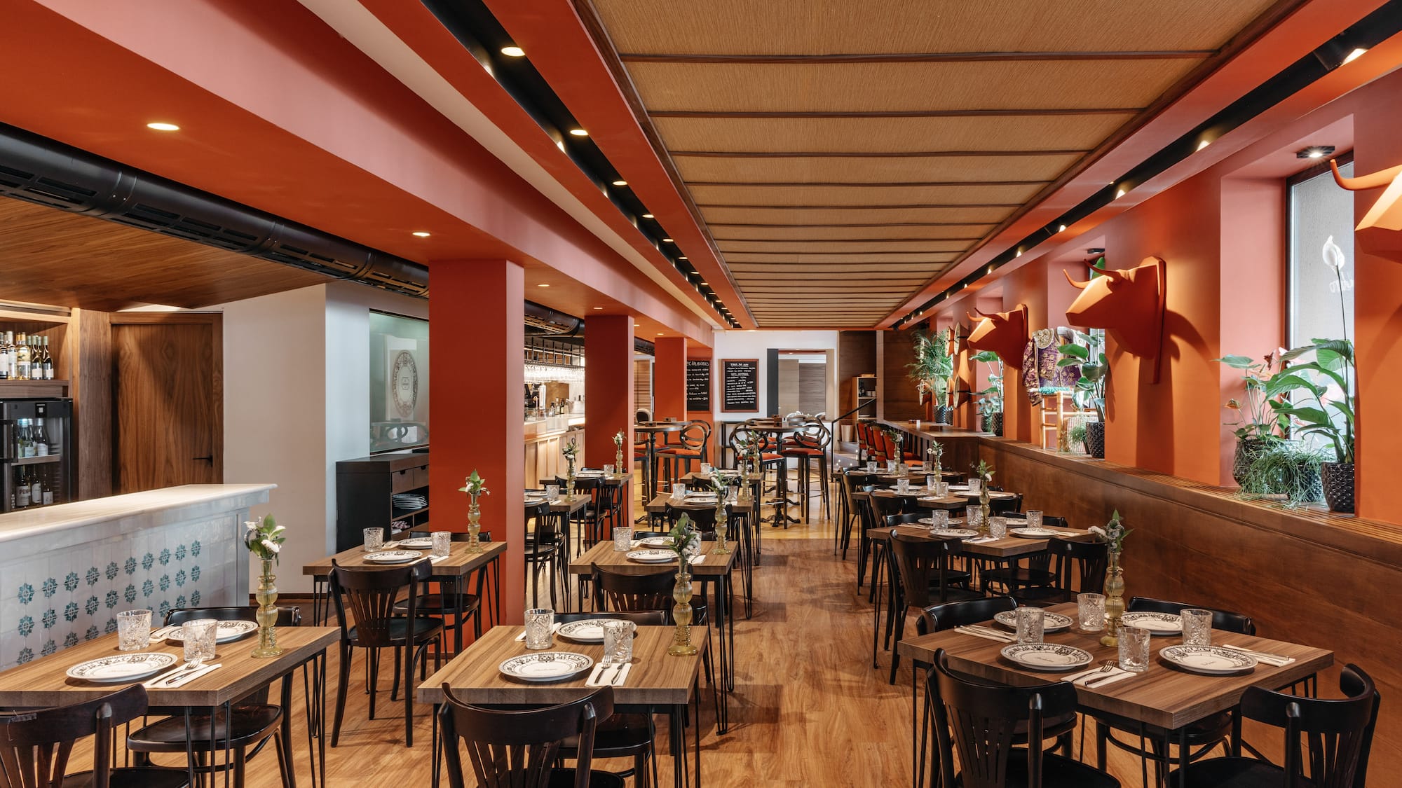 Restaurant dining area with orange walls, wooden tables, and bull head decor.