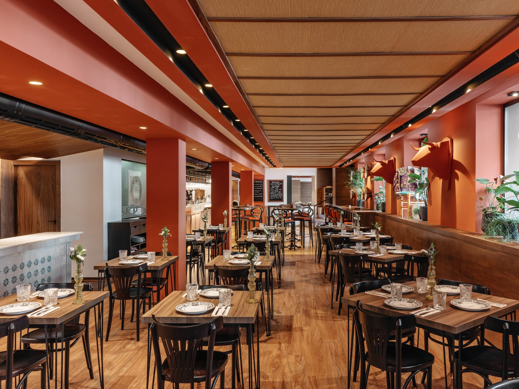 Restaurante con diseño naranja, mesas de madera y decoración taurina.