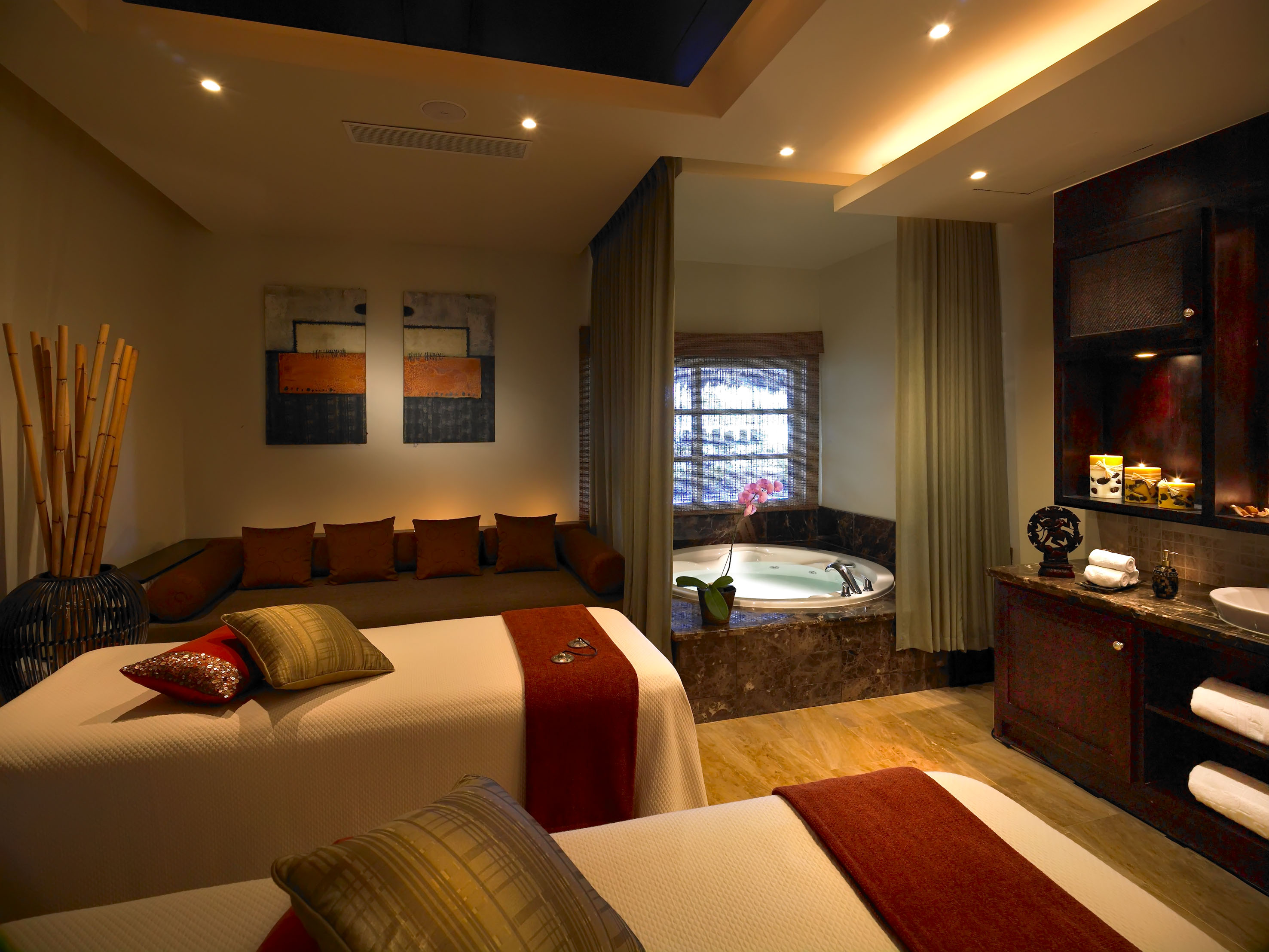 Luxurious spa treatment room with massage beds, jacuzzi, and warm lighting.