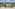 Luxury beachfront resort with white villas, pool, palm trees, and mountains.