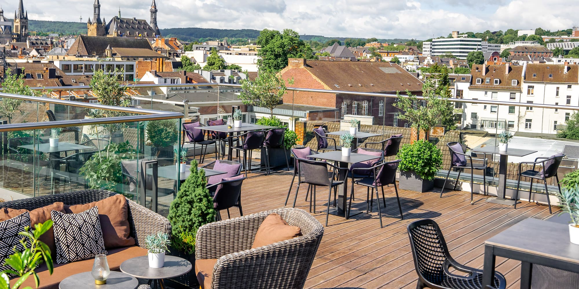 a rooftop patio with chairs and tables and plants