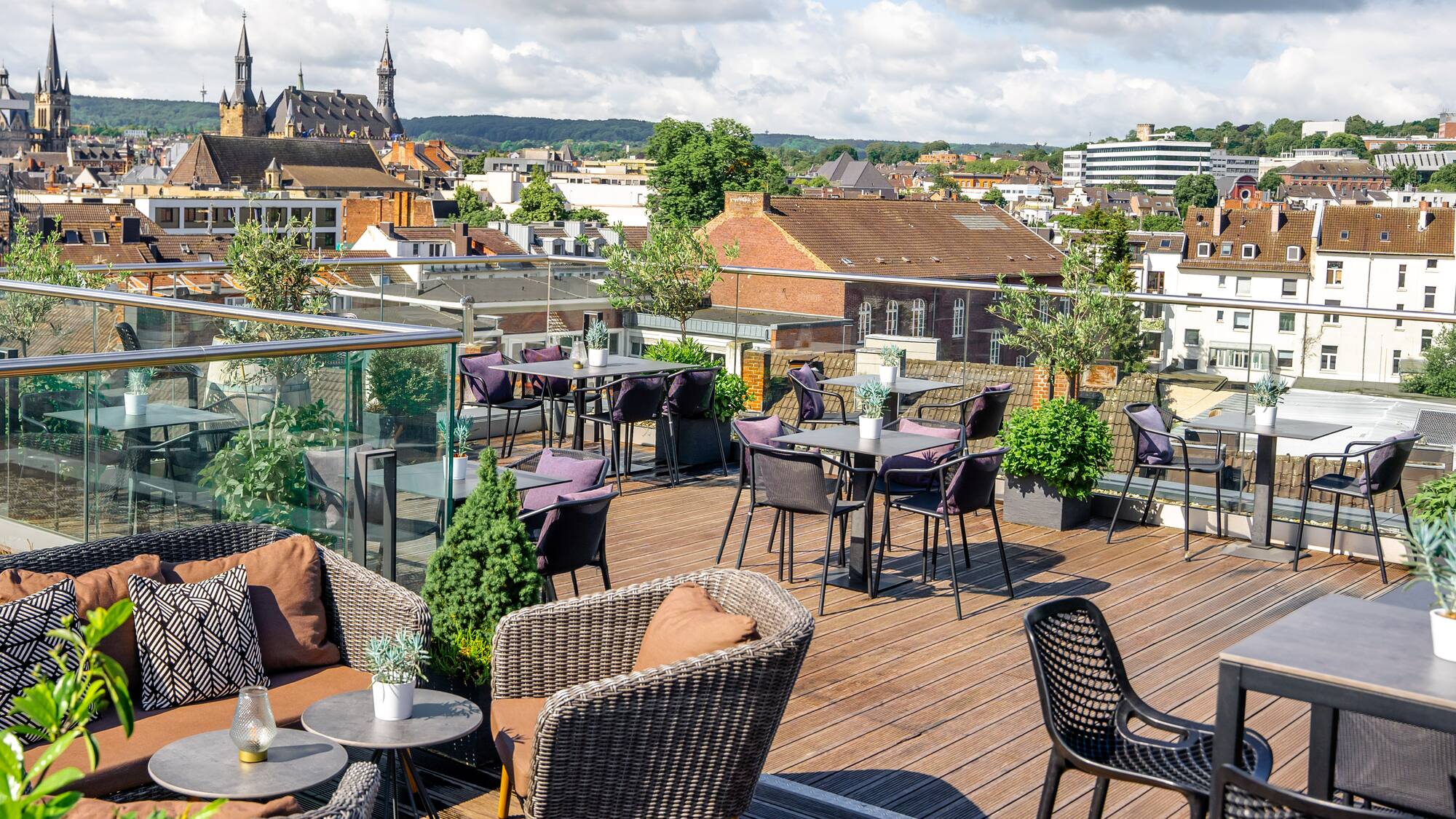 a rooftop patio with chairs and tables and plants