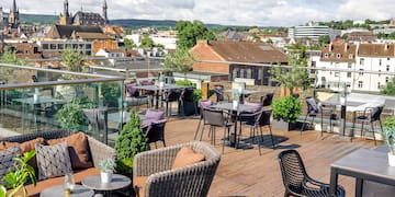 a rooftop patio with chairs and tables and plants