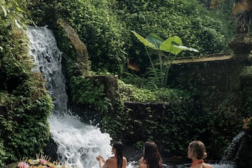 a group of women sitting in a river with a waterfall