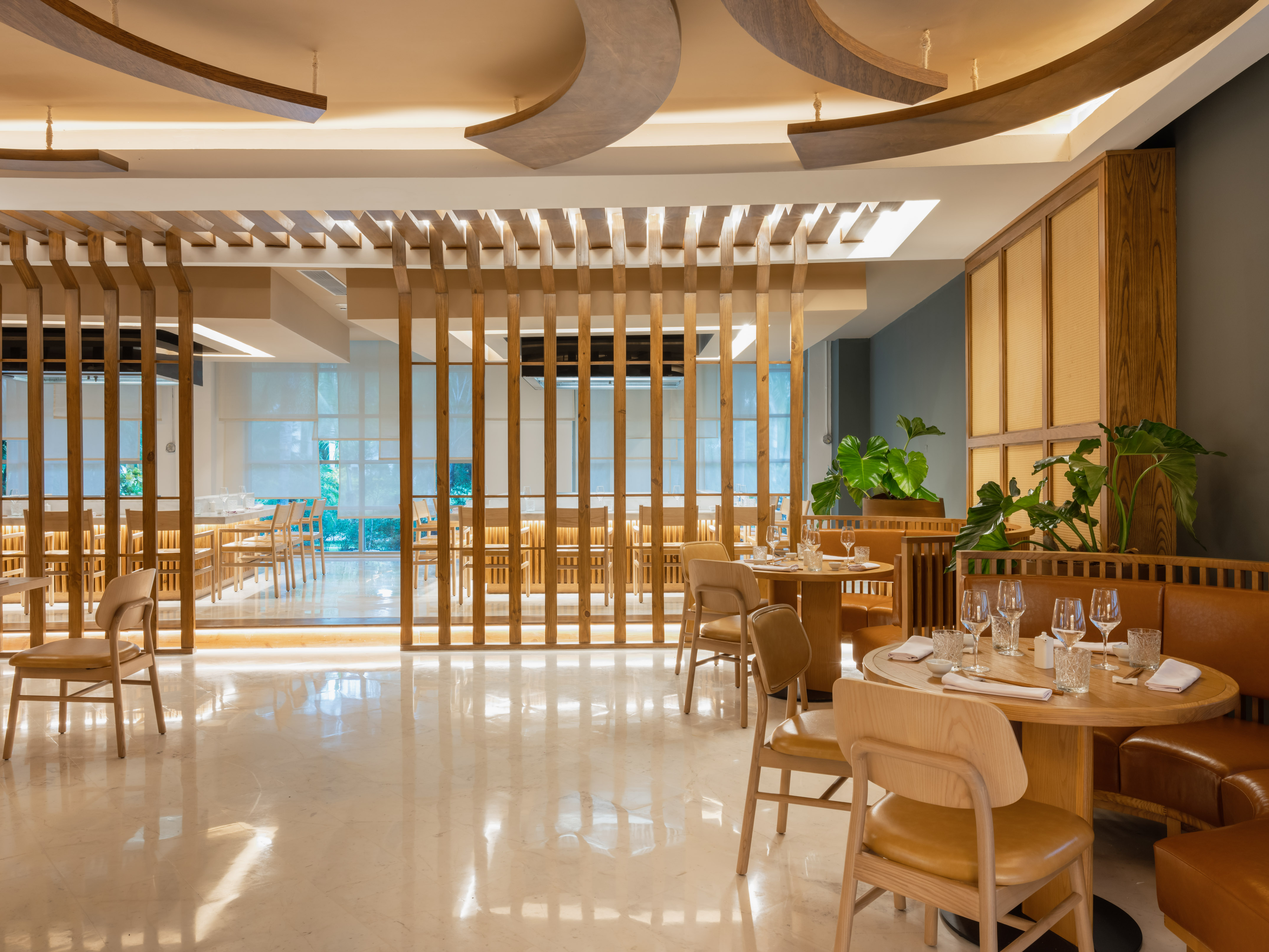 Modern restaurant interior with wooden partitions, marble floor, and elegant dining tables.