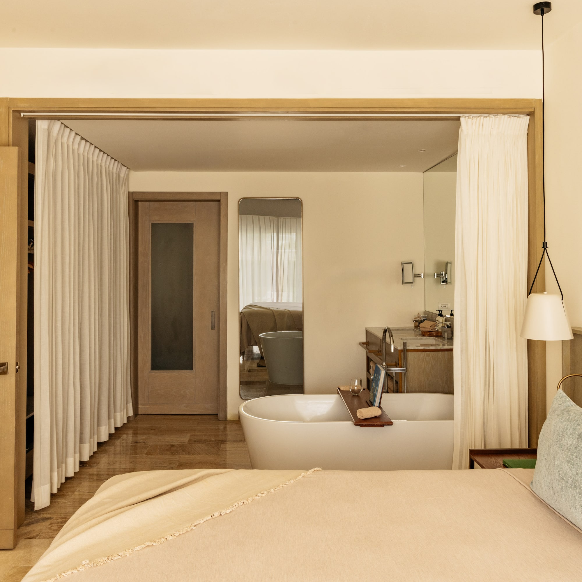 Luxury open-plan bedroom and bathroom with freestanding tub, modern design.